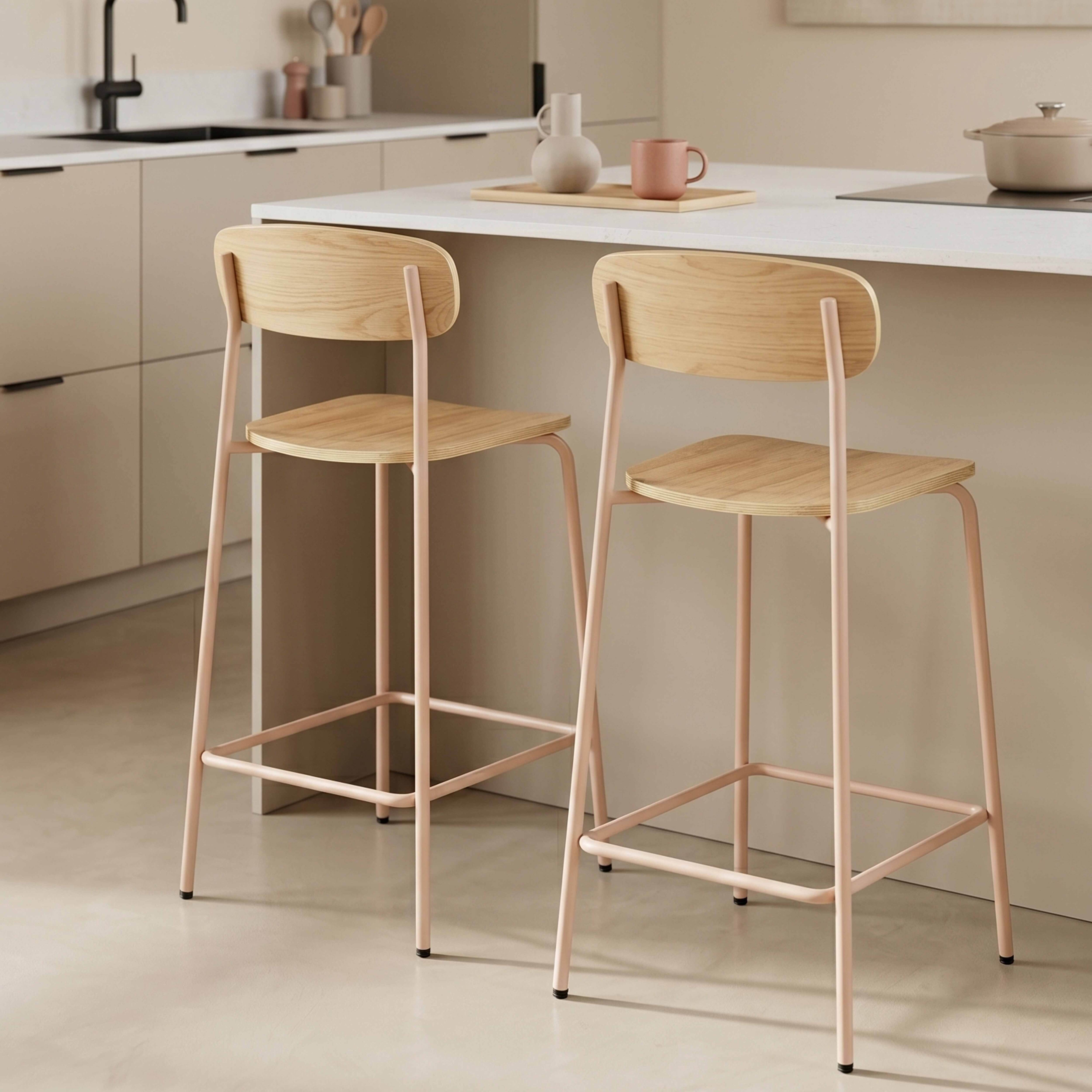 Zwei Holzbarhocker mit rosa Metallbeinen stehen vor einer Kücheninsel mit Topf.