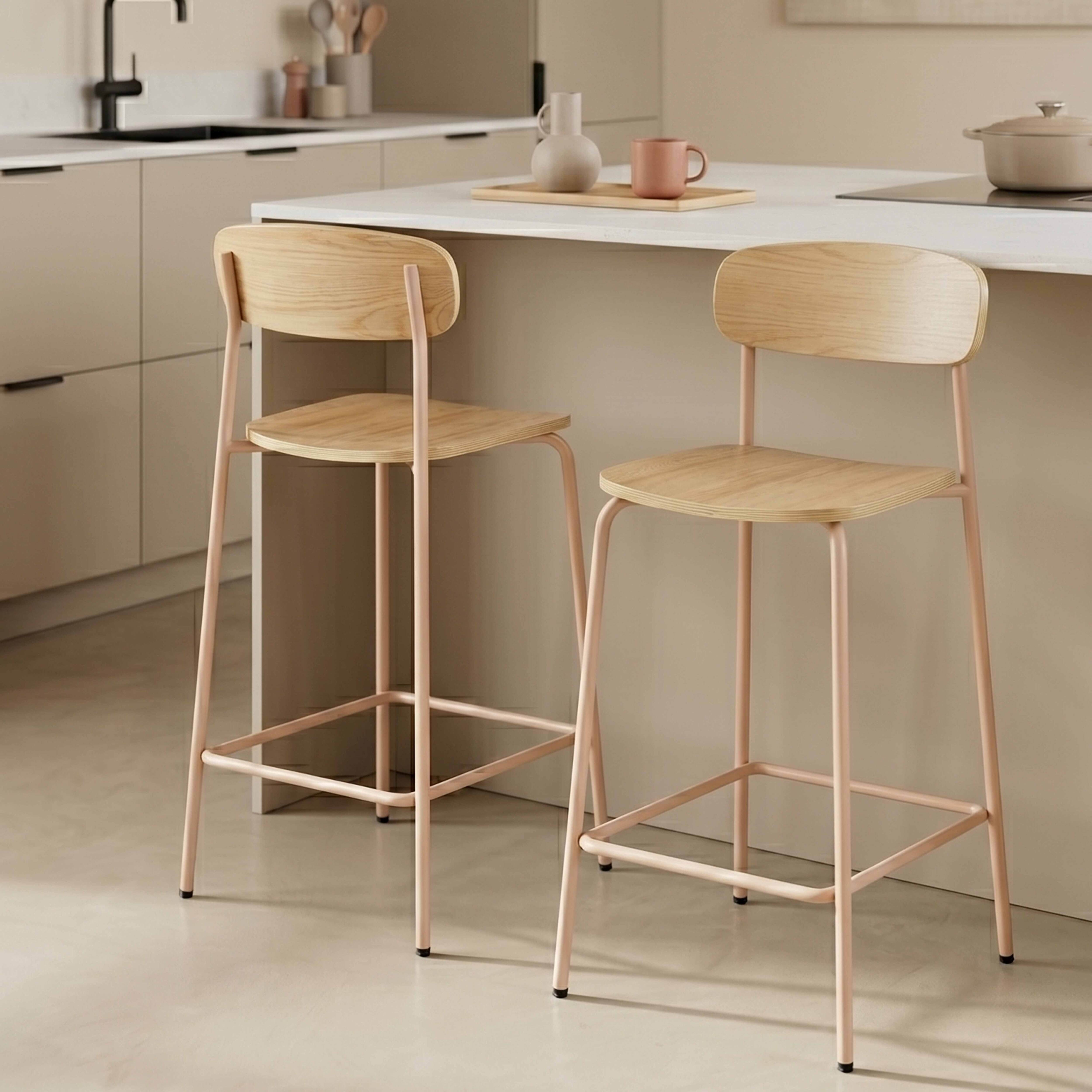 Zwei Holzbarhocker mit zarten rosafarbenen Metallbeinen in einer modernen Küche.
