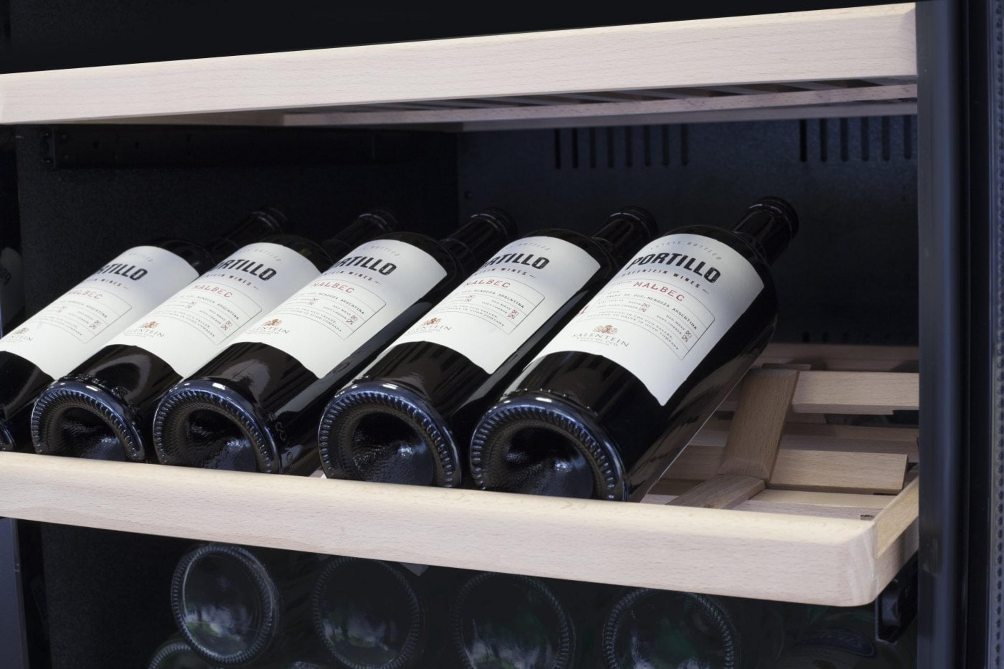Sechs Flaschen Rotwein der Marke Portillo Malbec liegen auf einem Holzboden.