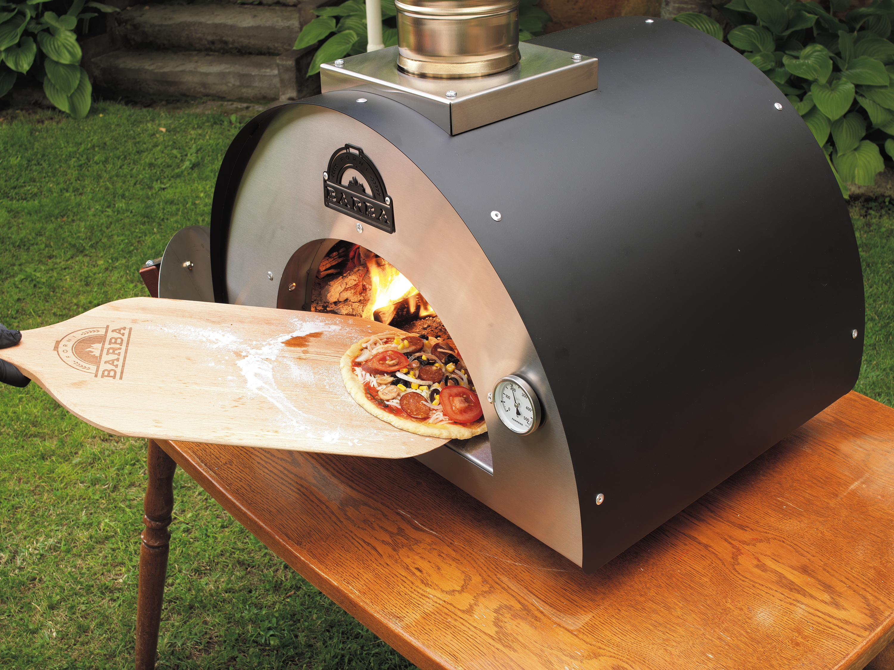 Ahşap bir kürekle pizza fırınına çiğ bir pizza sürülüyor.