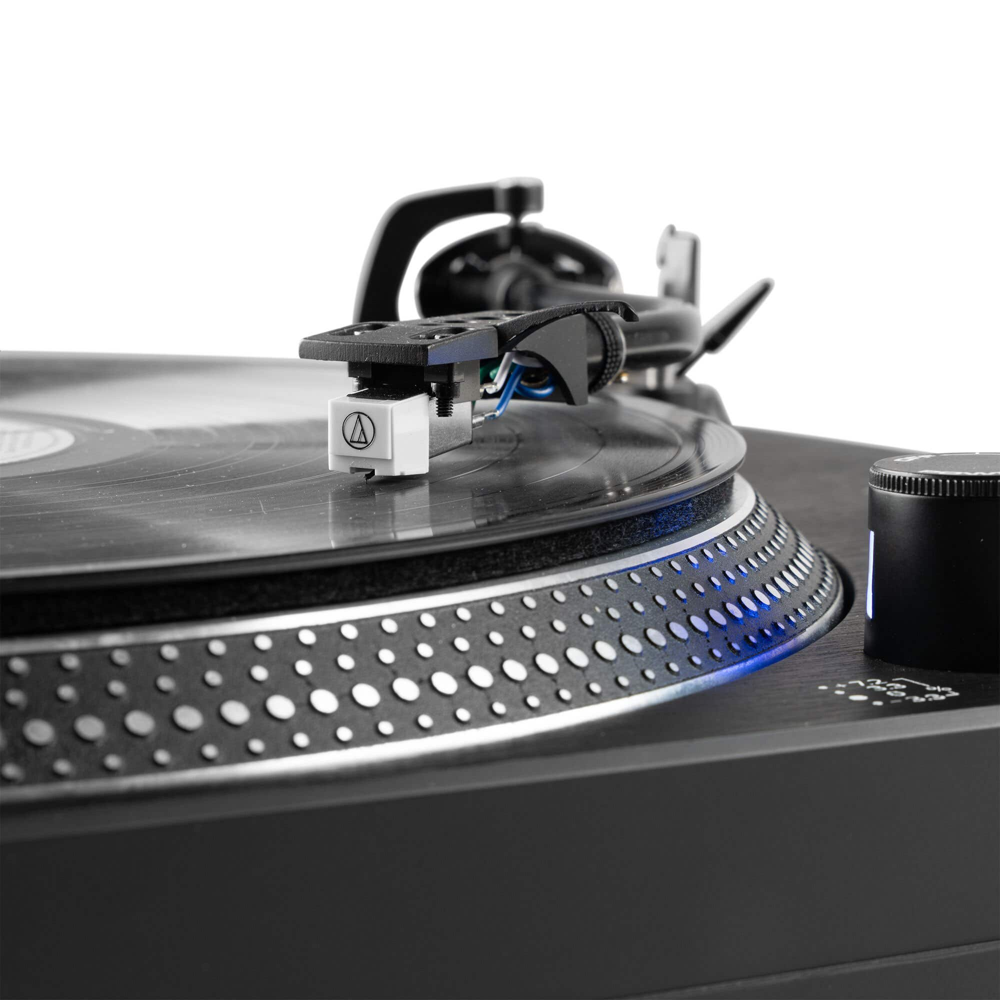 Primer plano de un tocadiscos negro con aguja en un disco de vinilo. Luces azules brillan.