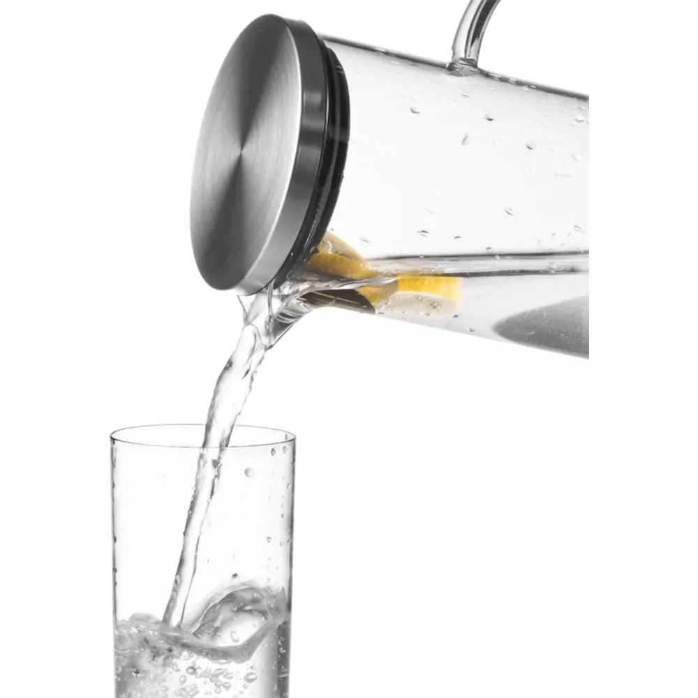 Wasser wird aus einer Karaffe mit Zitrone in ein Glas gegossen.