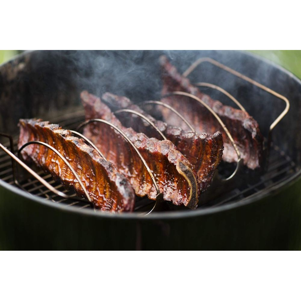 Rippchen auf einem Grill in einem Gestell, Rauch steigt auf.