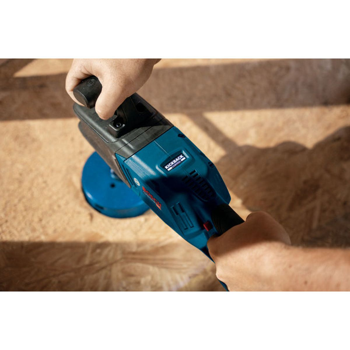 Una persona tiene un martello perforatore blu su una superficie di legno.