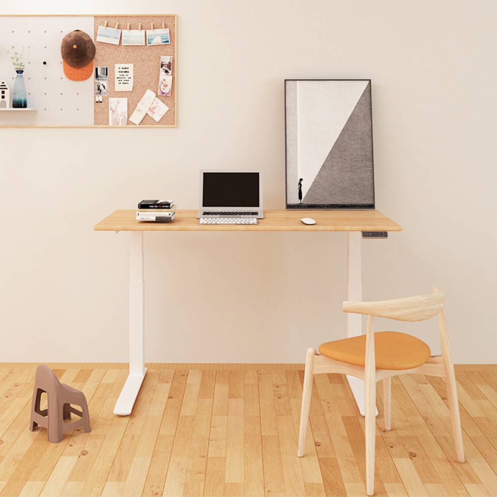 Ein höhenverstellbarer Schreibtisch mit Laptop, Büchern und einem Bild. Ein Stuhl steht daneben.