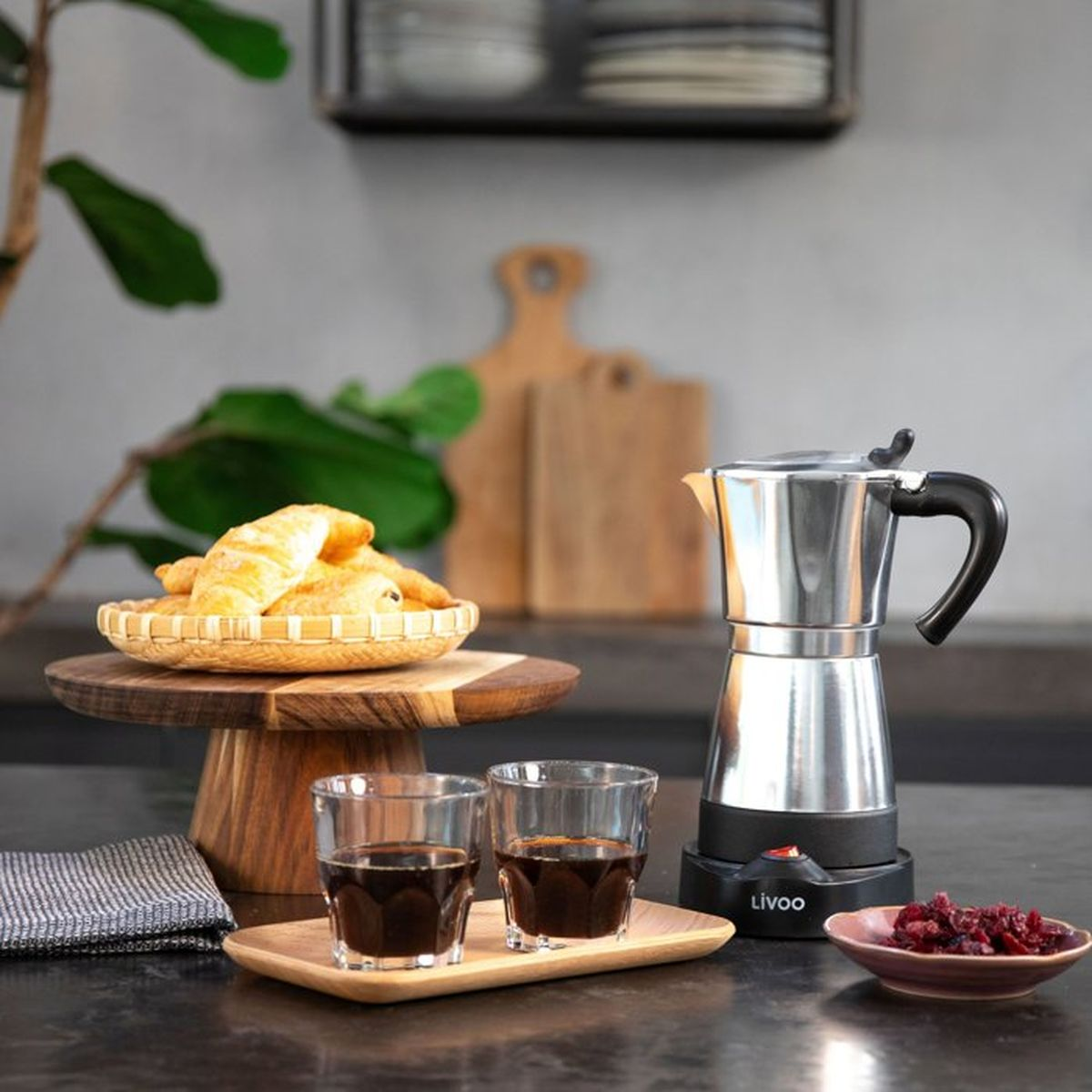 Moka con croissant, caffè e bacche su un bancone scuro.