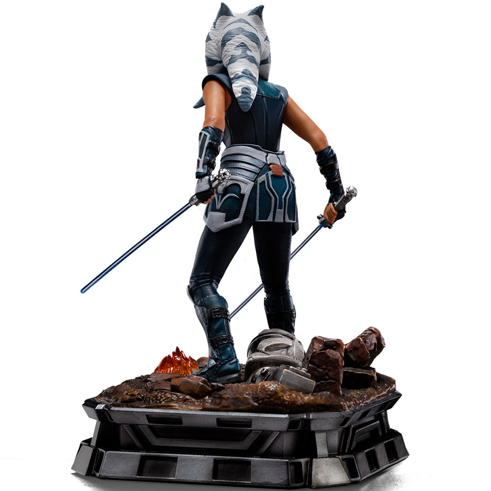 Eine Figur von Ahsoka Tano mit zwei Lichtschwertern auf einem felsigen Sockel mit einem Helm.