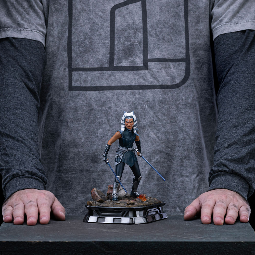 Figur von Ahsoka Tano mit Lichtschwertern auf einem felsigen Sockel.