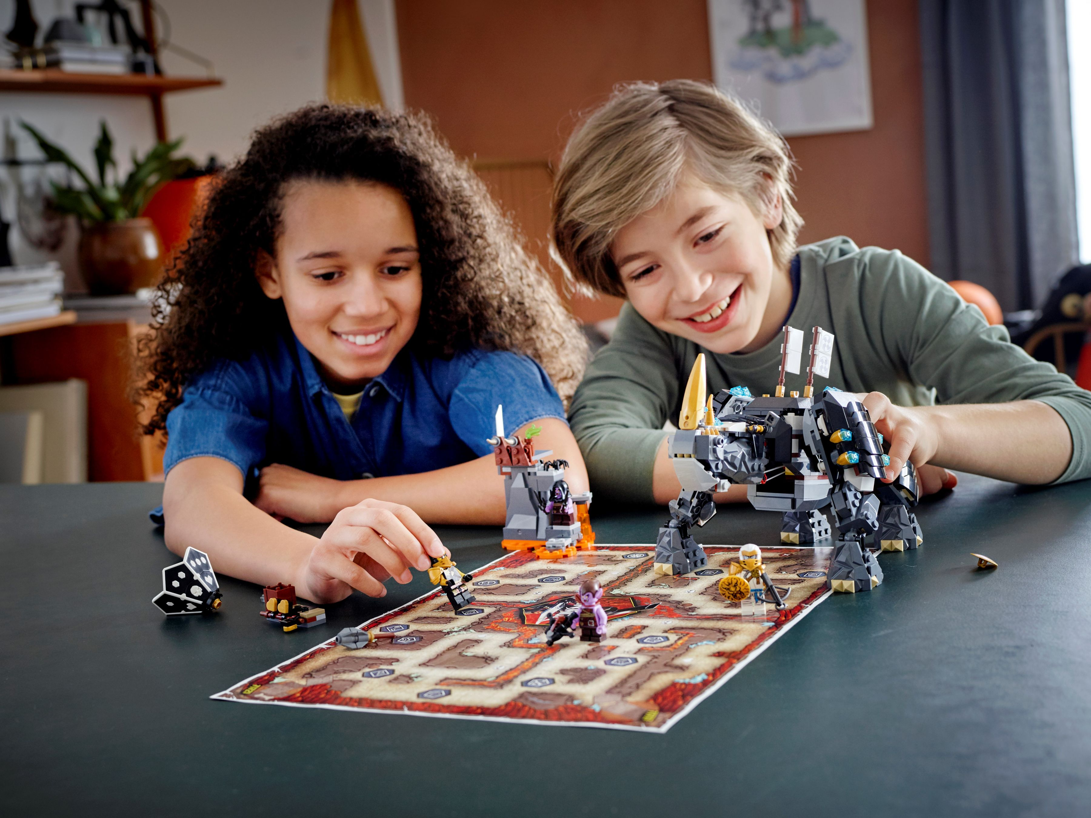 Zwei Kinder spielen mit Lego-Figuren und einem Spielbrett mit einem großen Lego-Roboter.