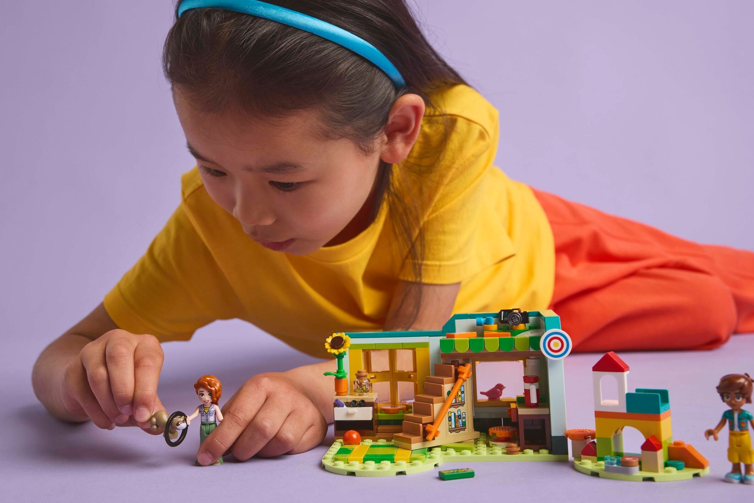 Ein Mädchen spielt mit Legosteinen, baut ein kleines Haus mit Figuren.
