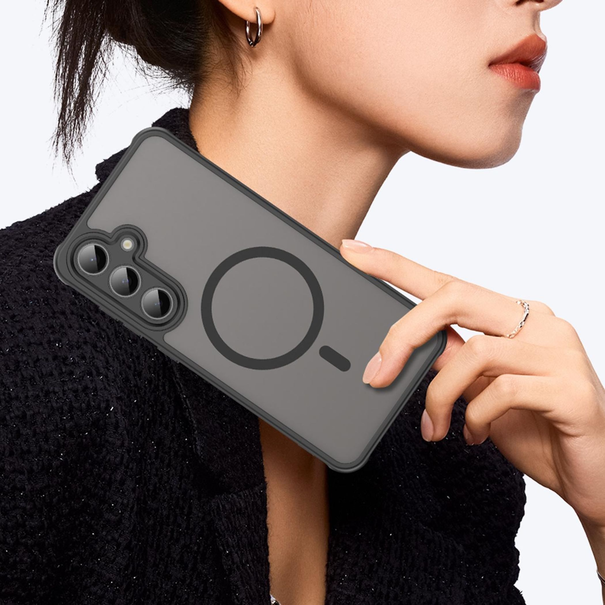 Eine Frau hält ein graues Handy mit drei Kameras und einem Magnetring.