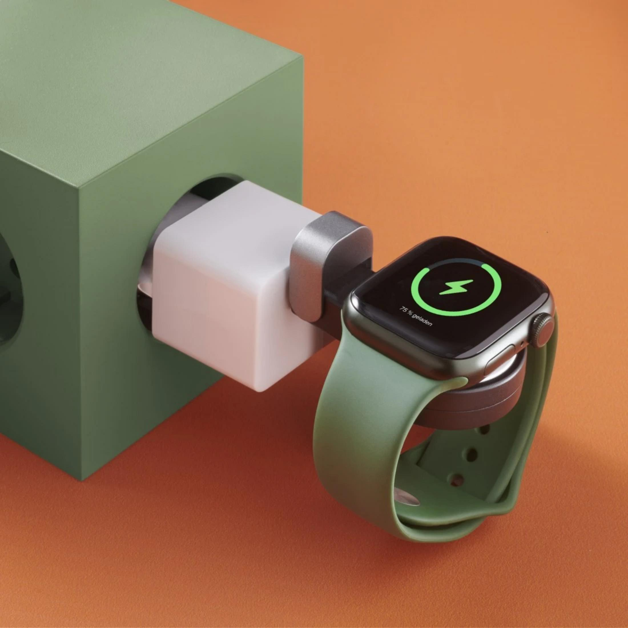 Grüne Smartwatch lädt an weißem Ladegerät vor orangefarbenem Hintergrund.