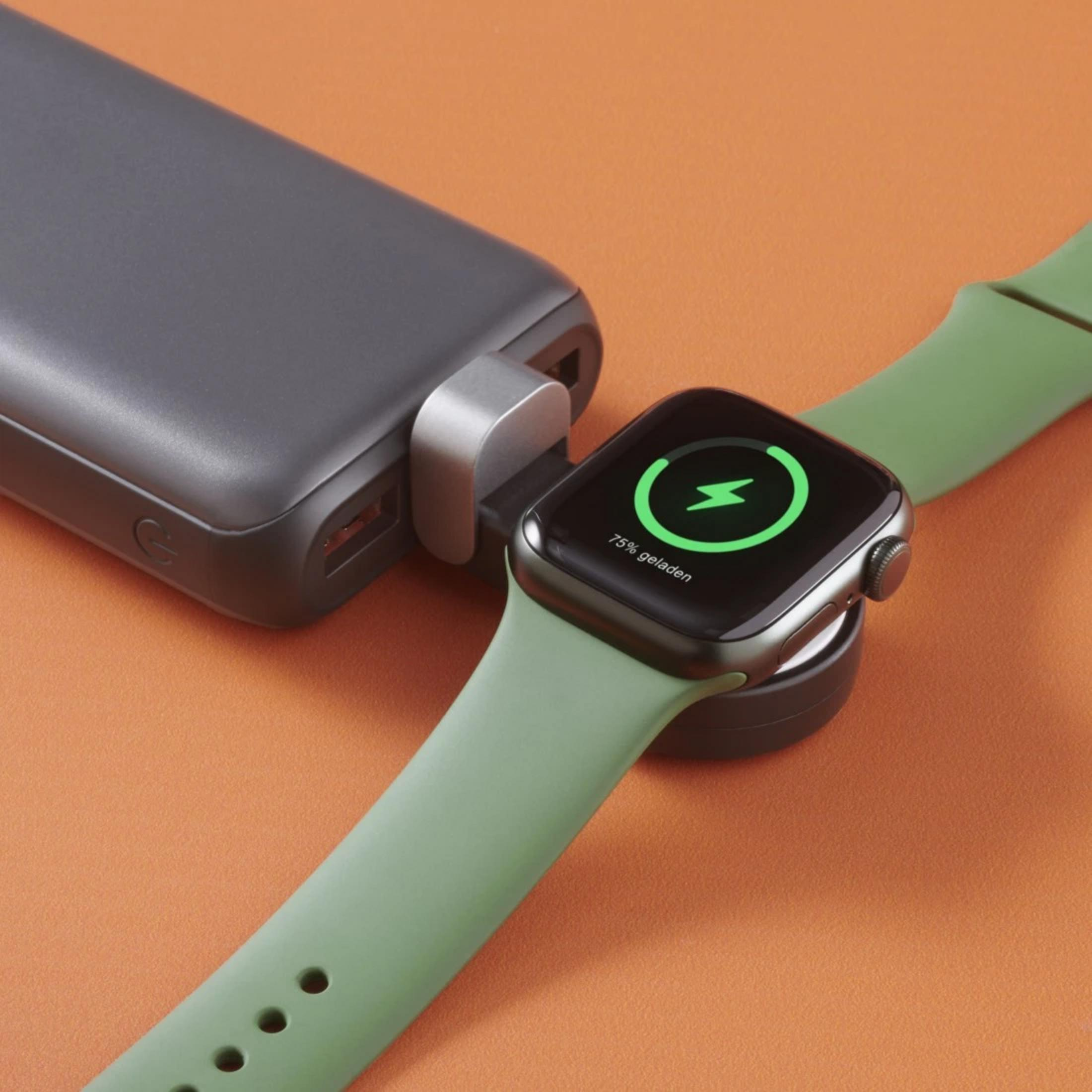 Eine dunkelgraue Powerbank ist an ein Smartwatch-Ladegerät angeschlossen. Die Uhr ist grün.
