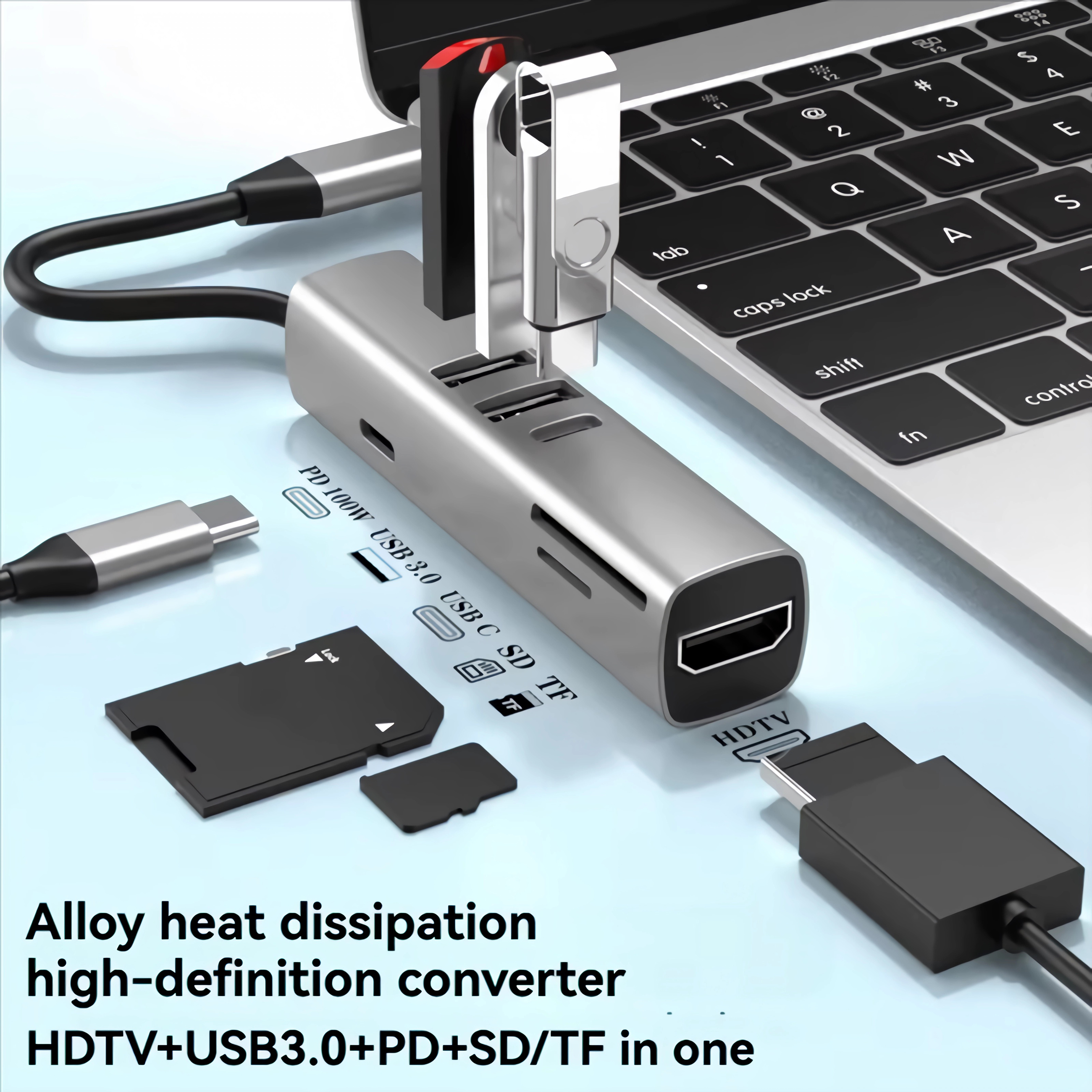 Ein silberner USB-C-Hub mit angeschlossenen Geräten neben einem Laptop.