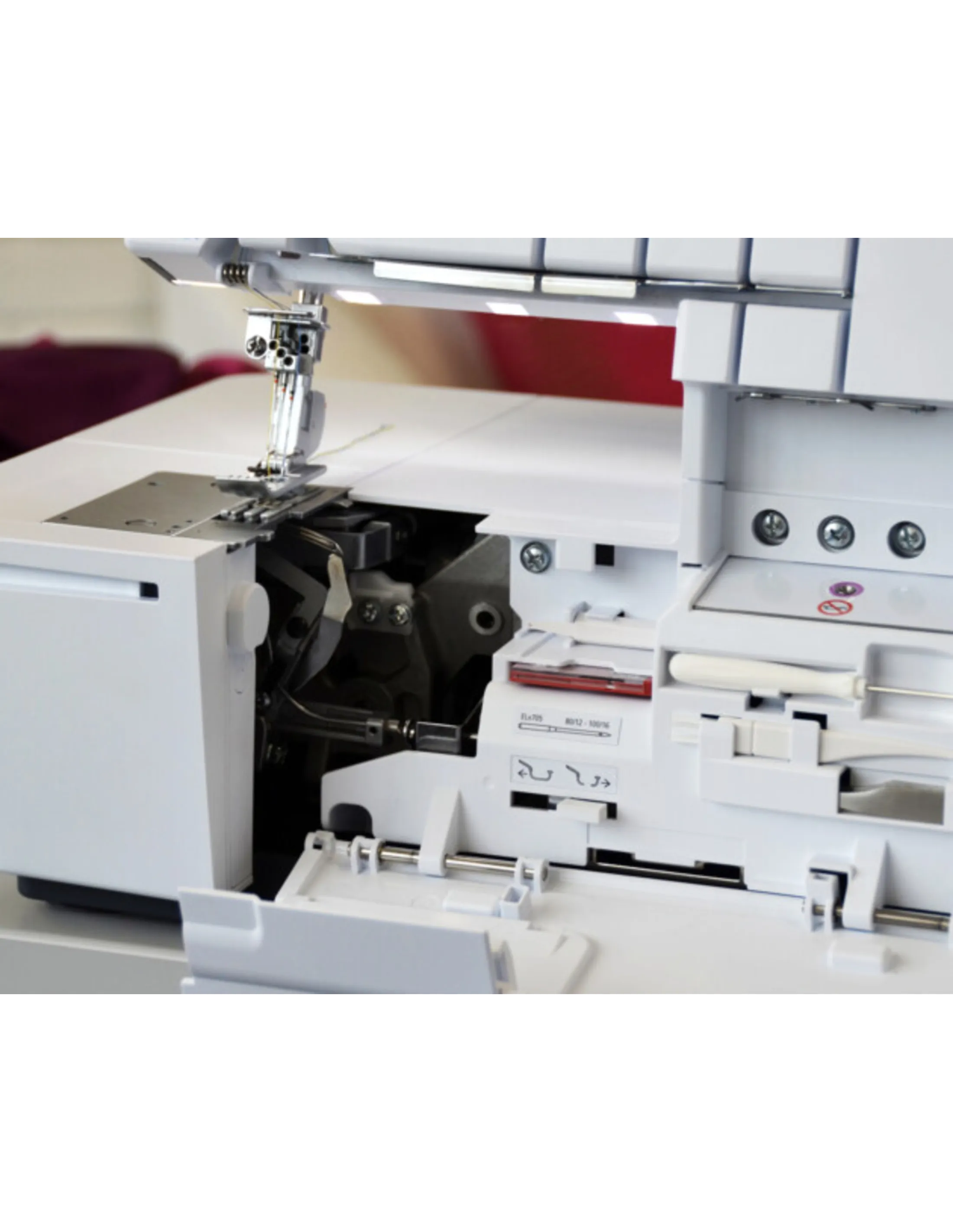 Close-up of a white sewing machine with exposed mechanical parts and needle.