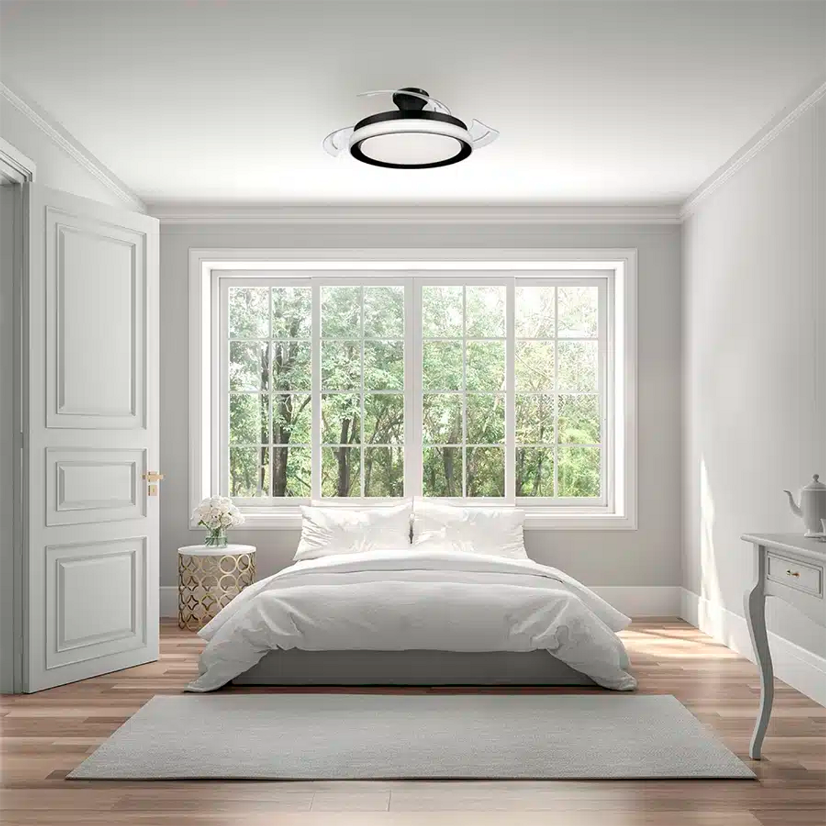 Dormitorio minimalista con cama blanca, ventana grande con árboles y ventilador de techo con luz.