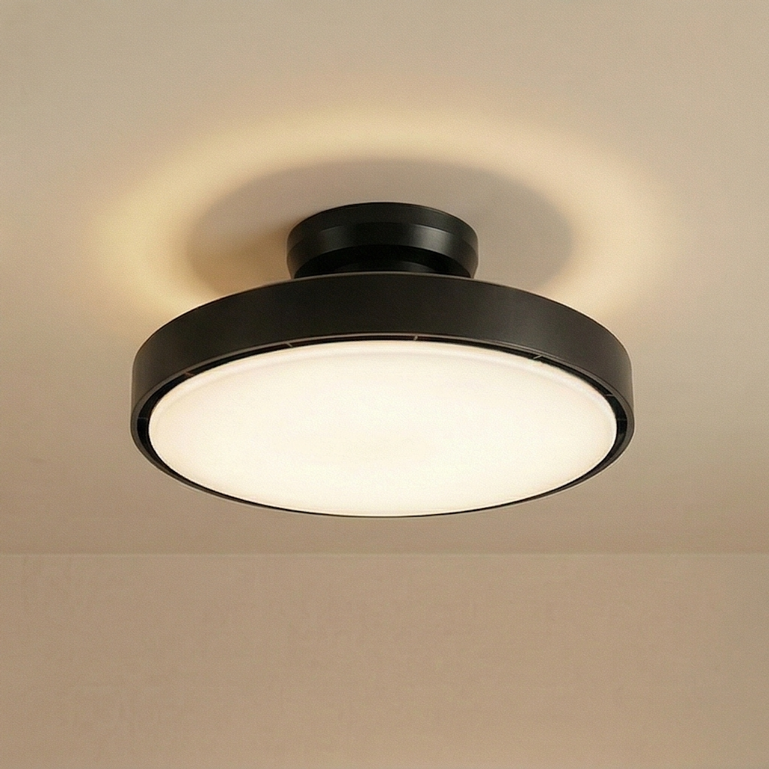 Una lámpara de techo redonda con borde negro y luz blanca sobre un techo color crema.