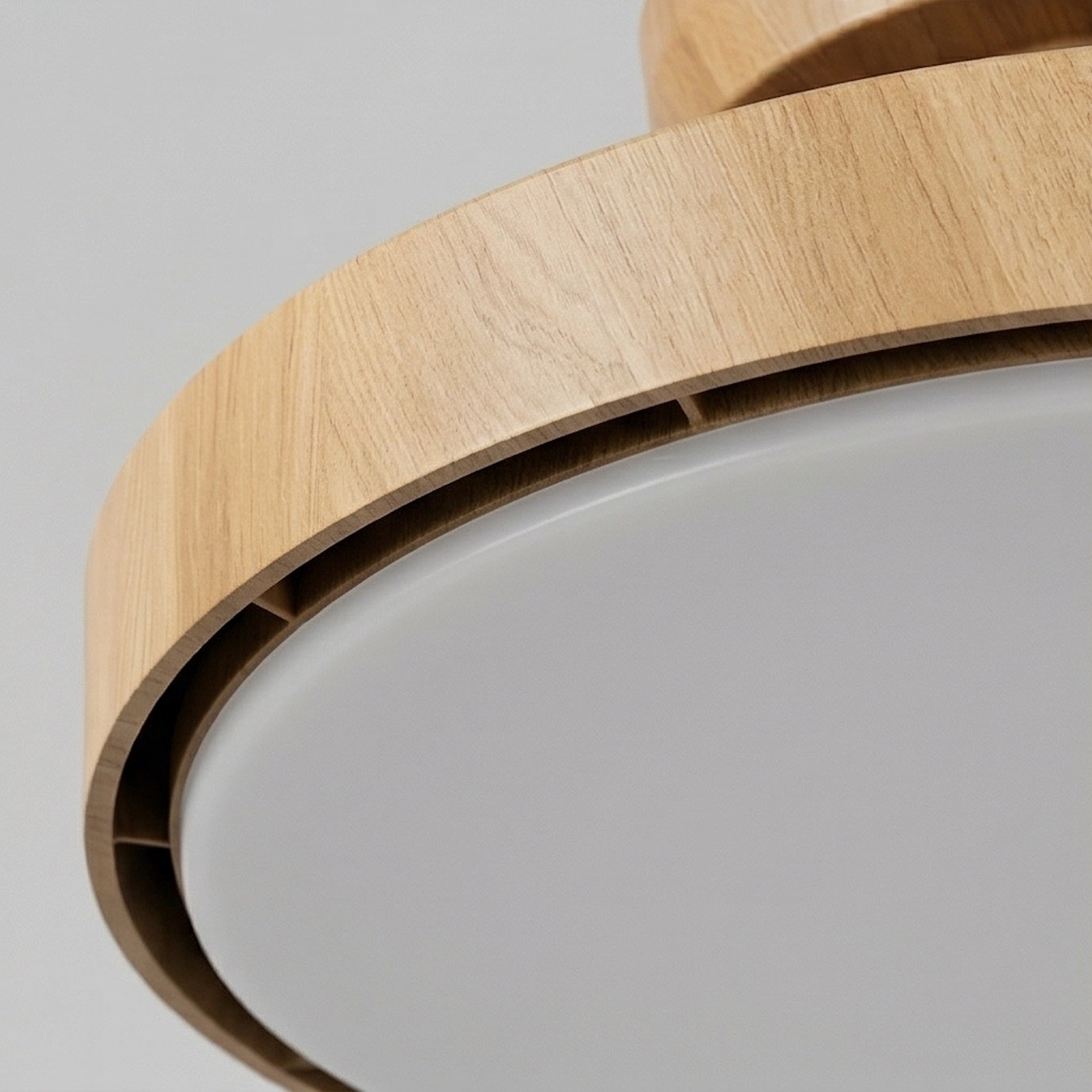 Primer plano de una lámpara de techo con borde de madera y difusor blanco.