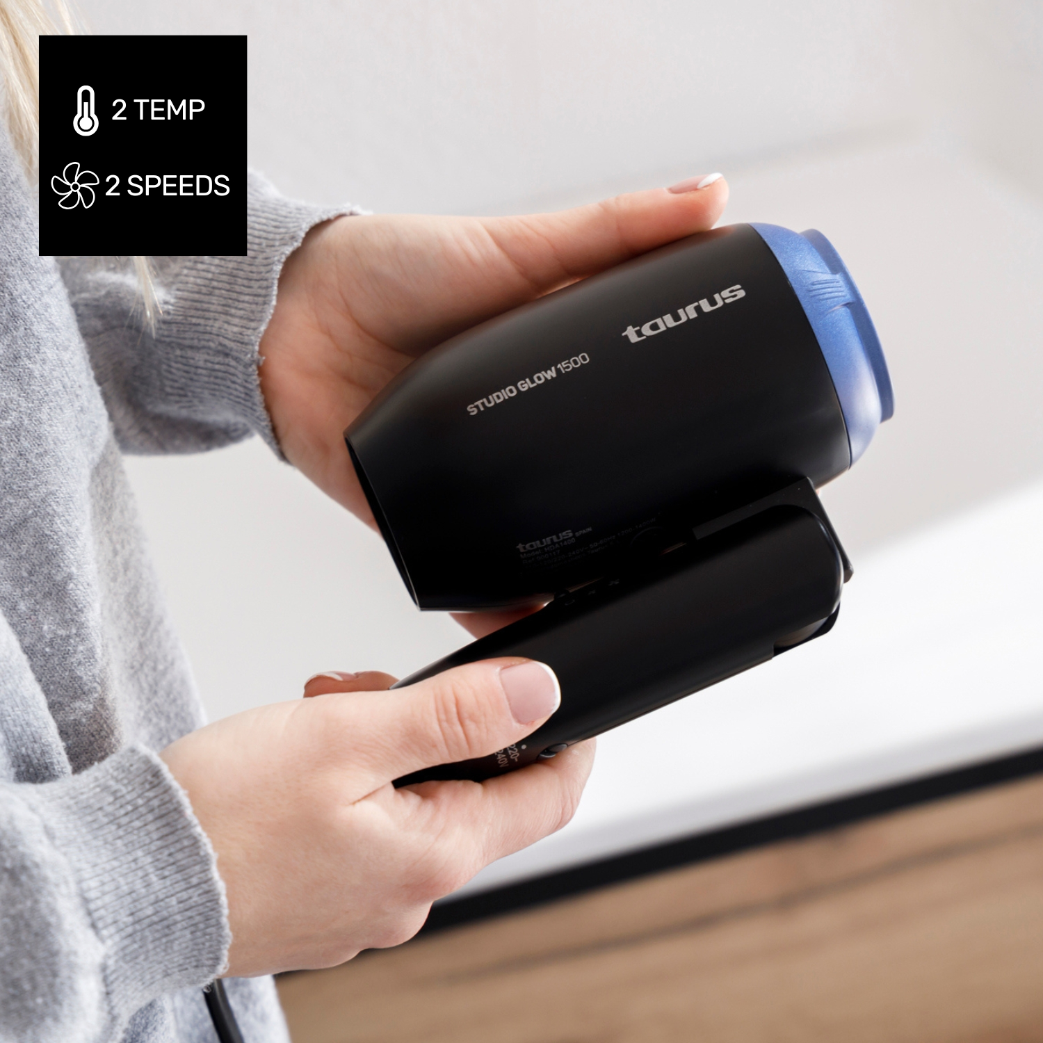 Persona sosteniendo secador de pelo negro con detalles azules y logo Taurus.