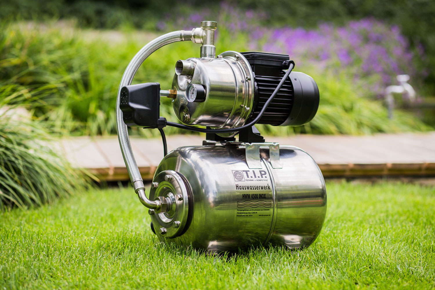Edelstahl Hauswasserwerk mit schwarzem Motor auf grünem Rasen.
