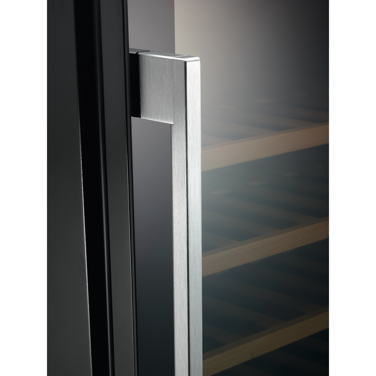 Elegante manija plateada en un refrigerador oscuro, estantes de madera.