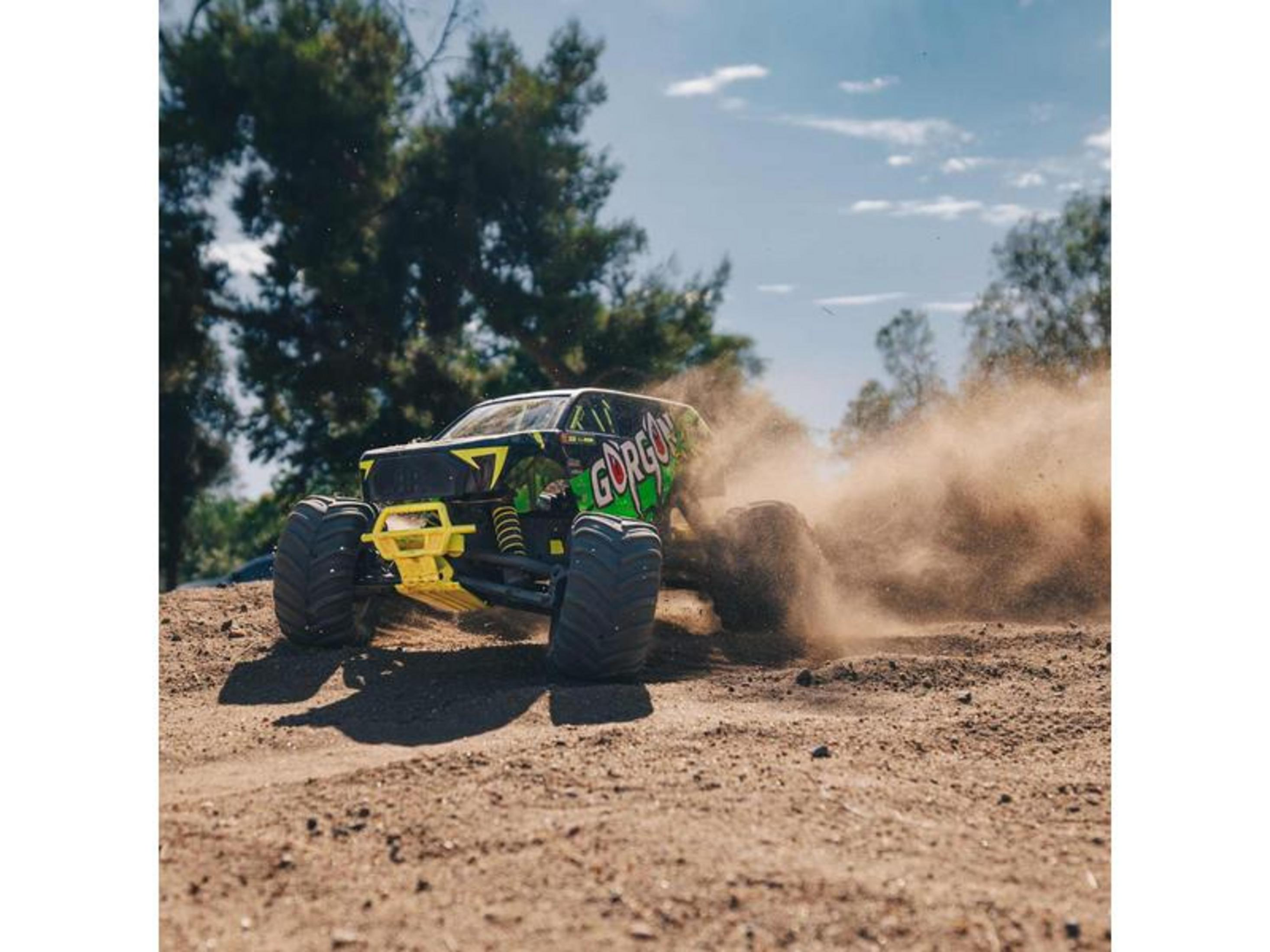 Un monster truck RC amarillo con letras verdes "Gorgon" conduce por un camino de tierra.