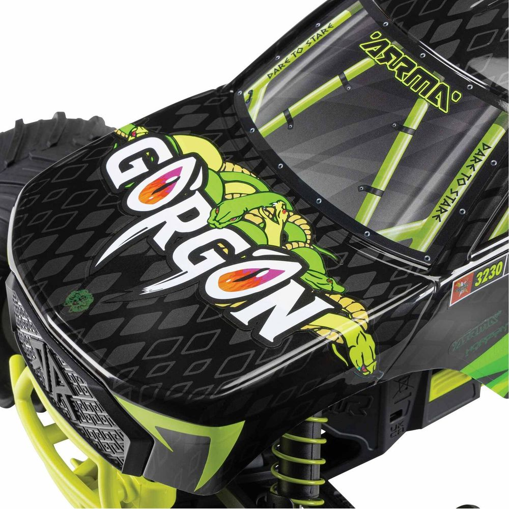 Coche RC negro con gráfico de serpiente 'Gorgon', jaula antivuelco verde y amortiguadores amarillos.