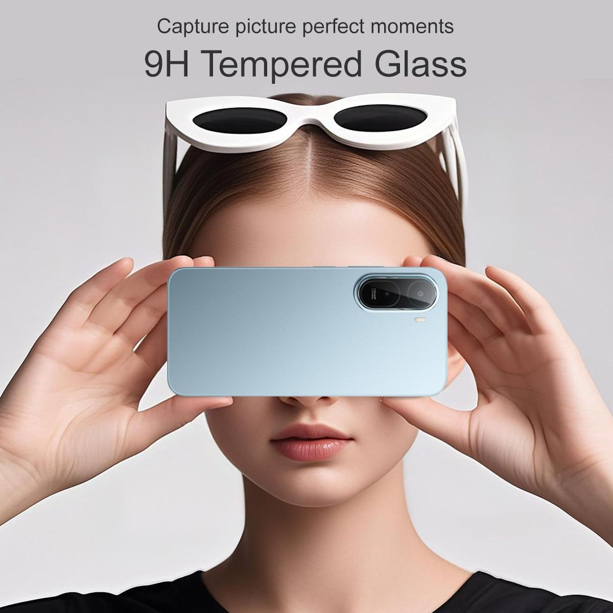 Una donna tiene uno smartphone azzurro davanti al viso, occhiali da sole bianchi in testa.