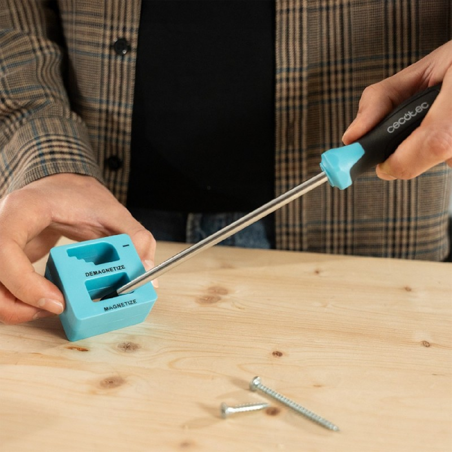 Persona sostiene destornillador y herramienta azul magnetizar/desmagnetizar con tornillos.