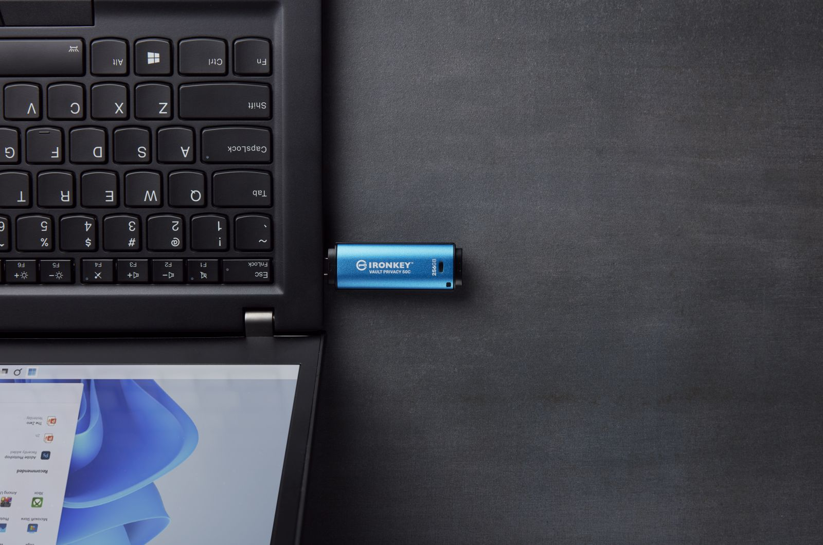 Unità USB IronKey blu inserita in un laptop, tastiera e schermo visibili.