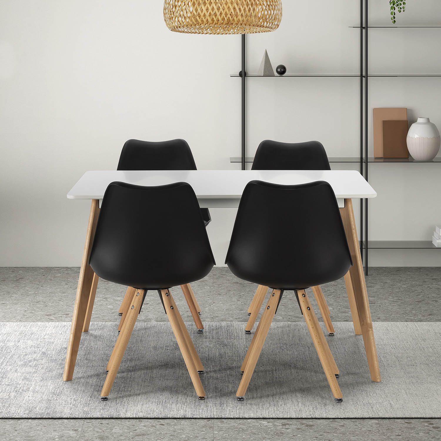 Una mesa blanca con cuatro sillas negras con patas de madera en un comedor.