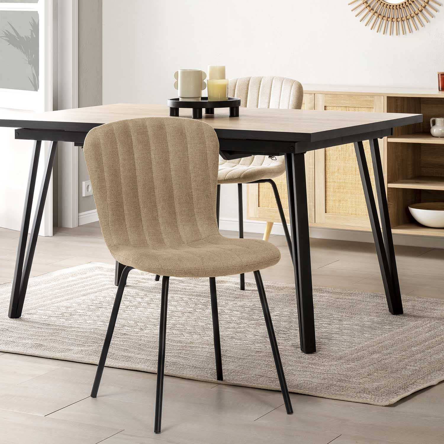 Una silla de comedor beige delante de una mesa de madera con patas negras.