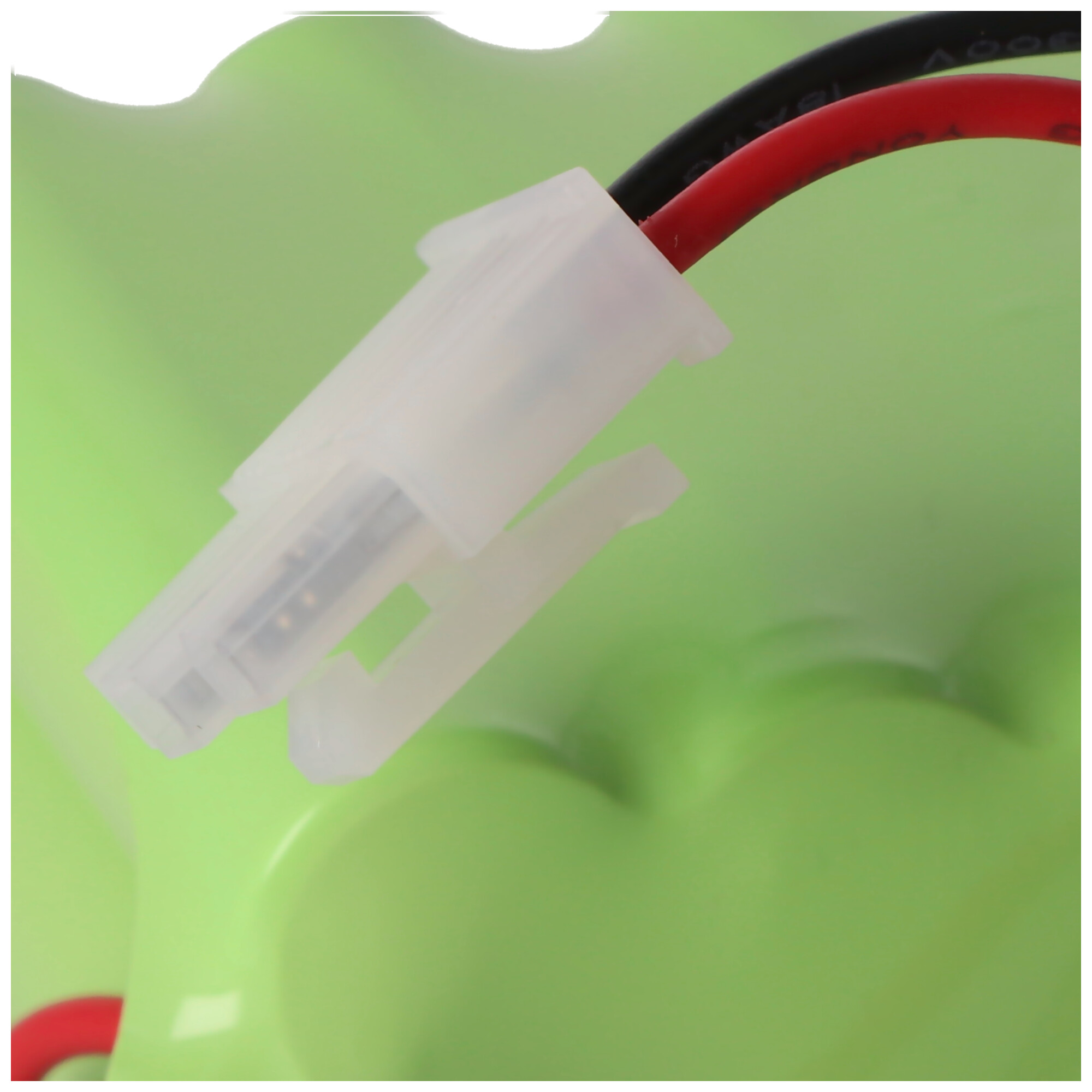 Grüner Akku mit weißem Stecker und roten/schwarzen Kabeln.
