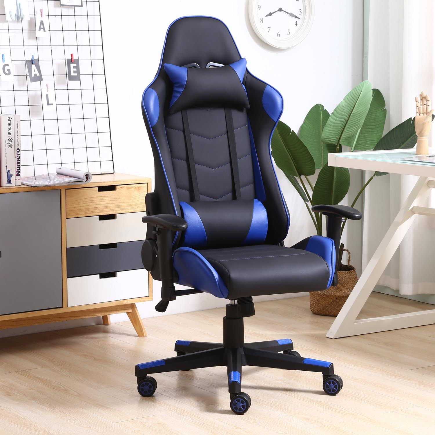 Una silla gamer negra y azul sobre suelo de madera, junto a un mueble y un escritorio.