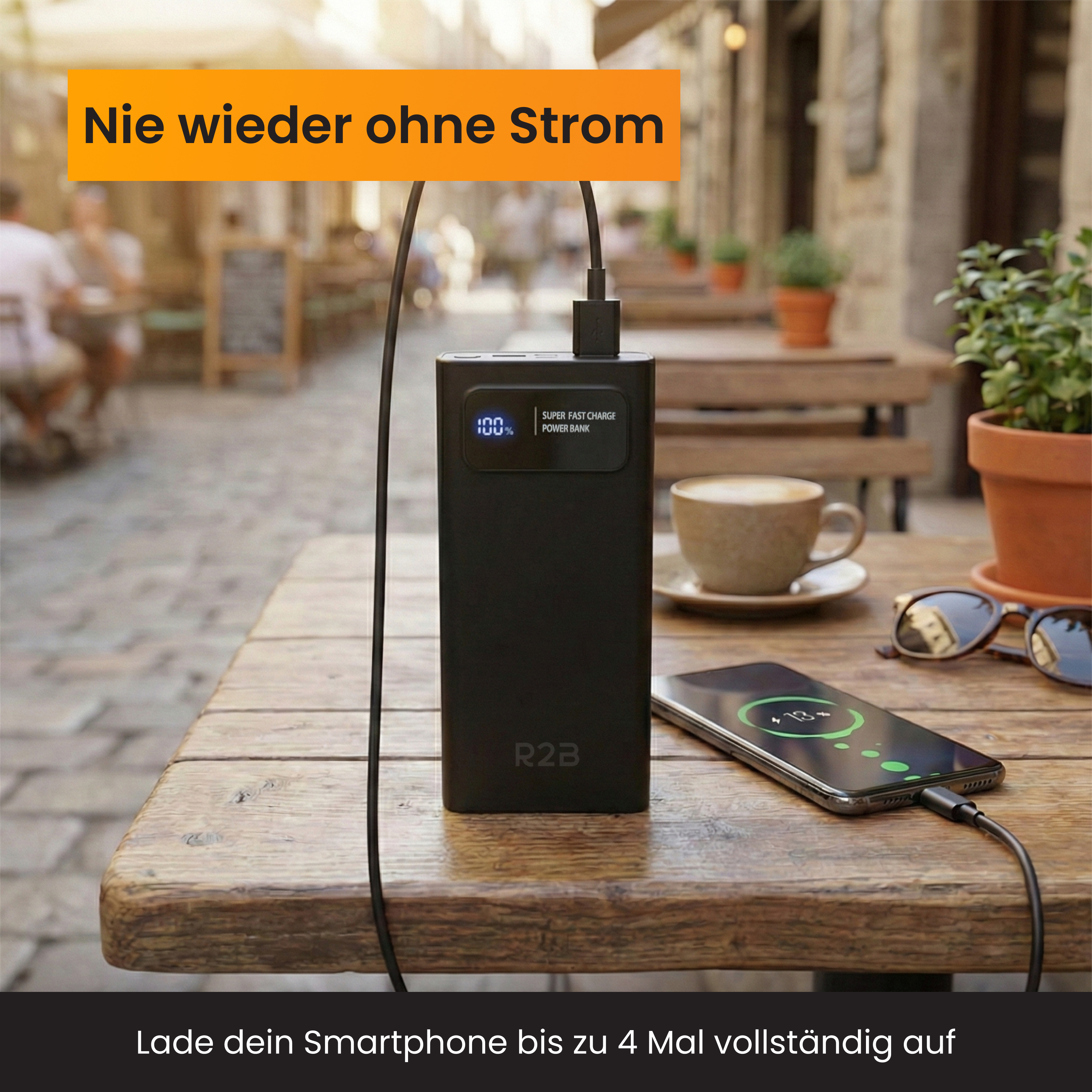 Schwarzes R2B Powerbank lädt ein Smartphone auf einem Holztisch.