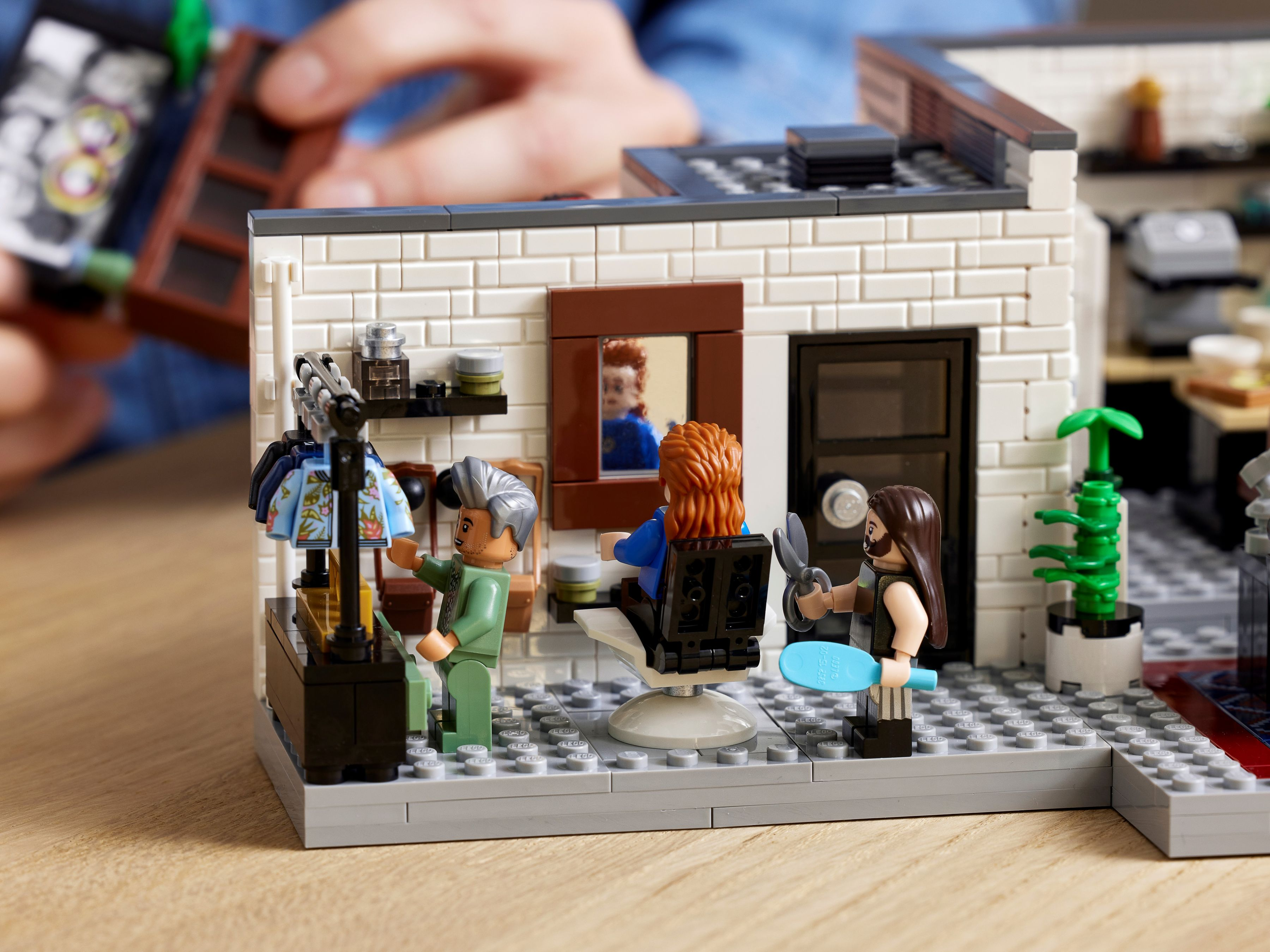 Lego-Friseursalon mit zwei Figuren, einer im Stuhl, einer schneidend.
