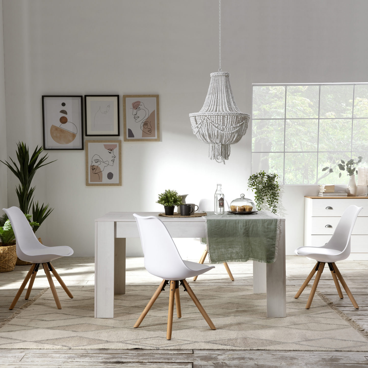 Comedor moderno con mesa blanca, cuatro sillas y arte de pared.