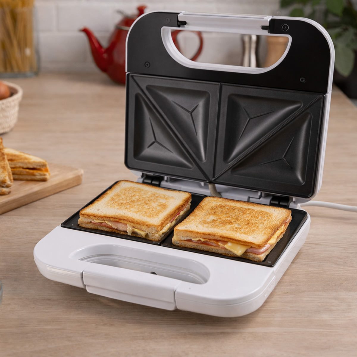 Una sandwichera abierta con dos sándwiches dorados cocinándose dentro.
