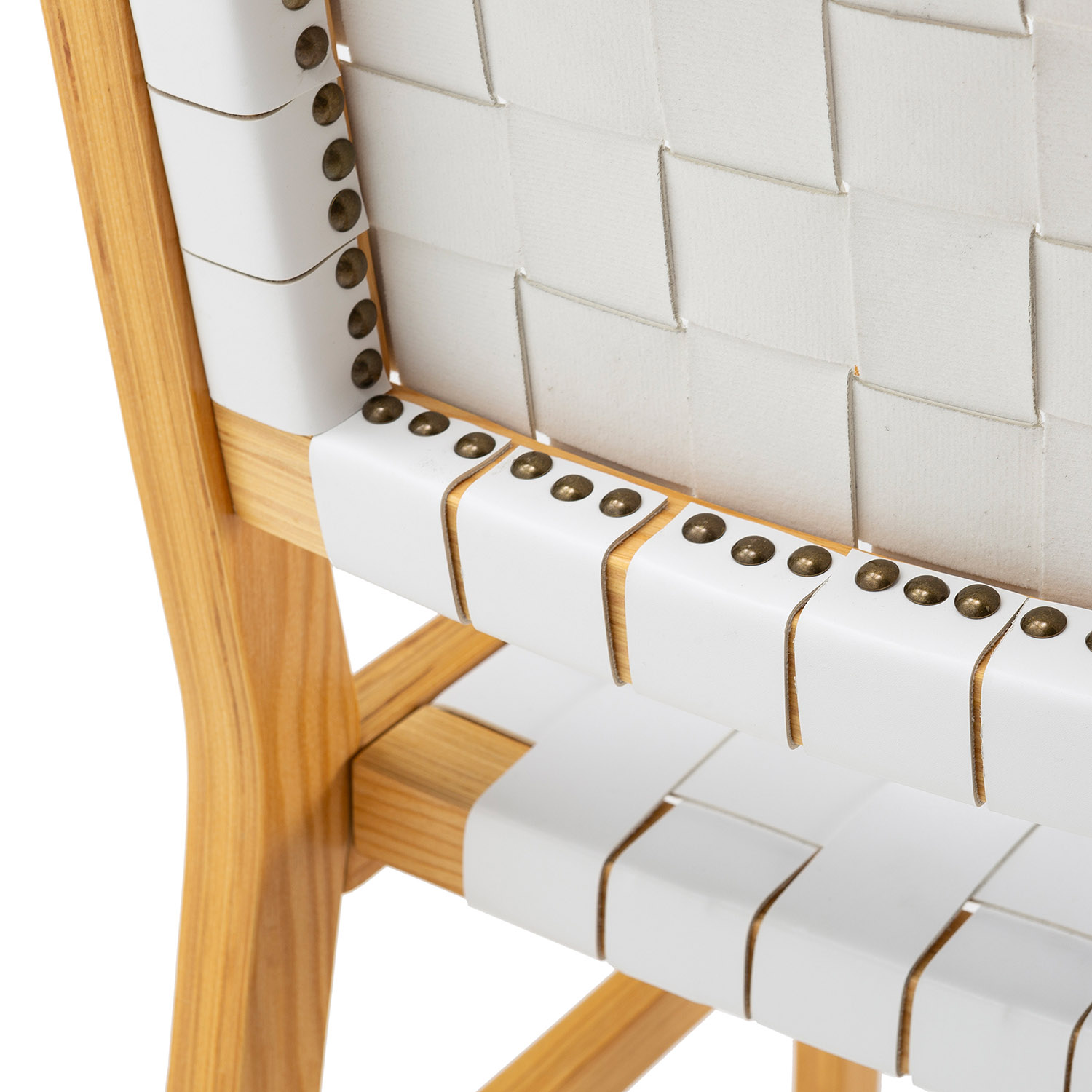 Primer plano de una silla de madera con correas tejidas blancas y remaches de latón.