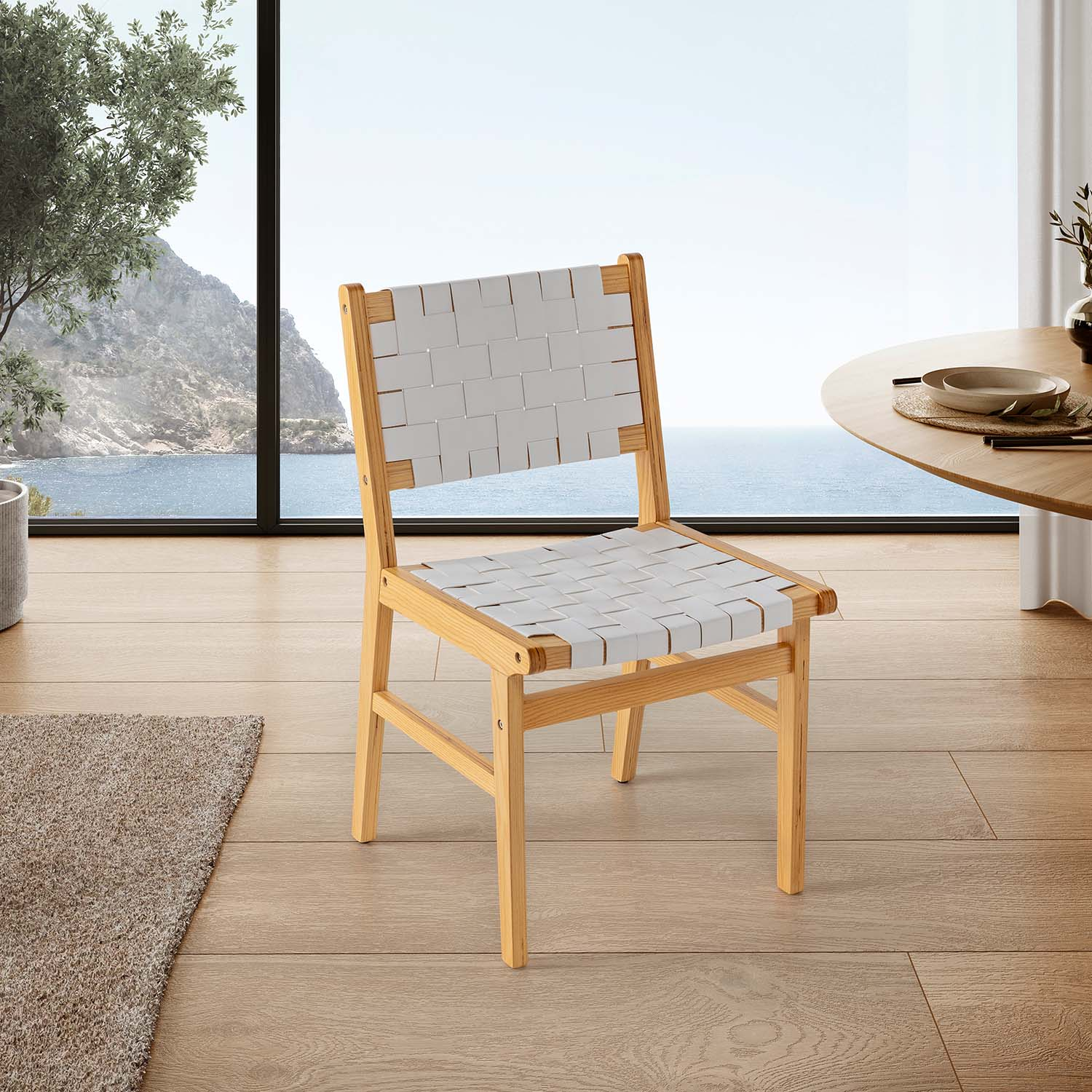 Una silla de madera con tela tejida blanca se sienta en un suelo de madera con vistas al mar.