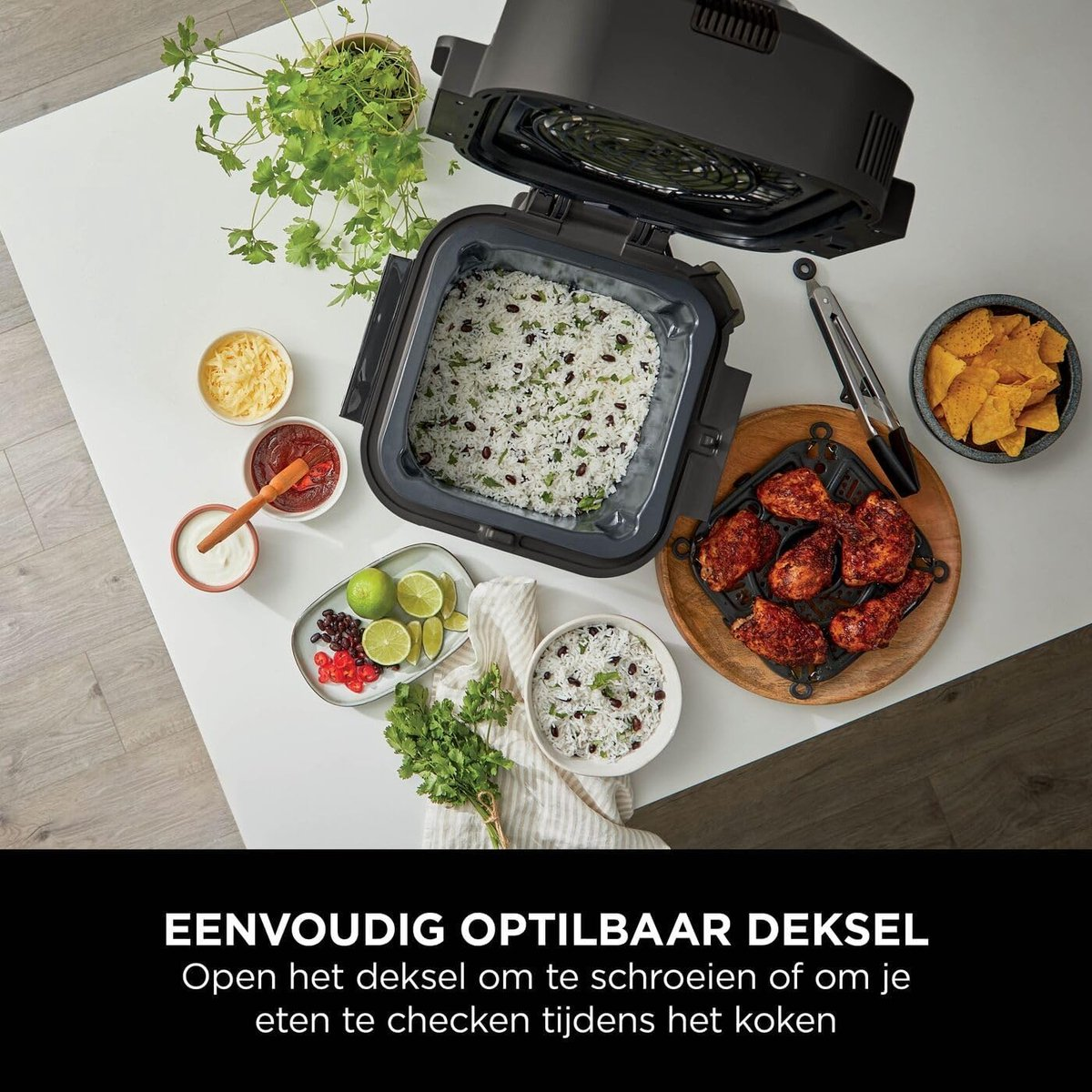 An open air fryer on a table with rice, chicken, chips, and side dishes.