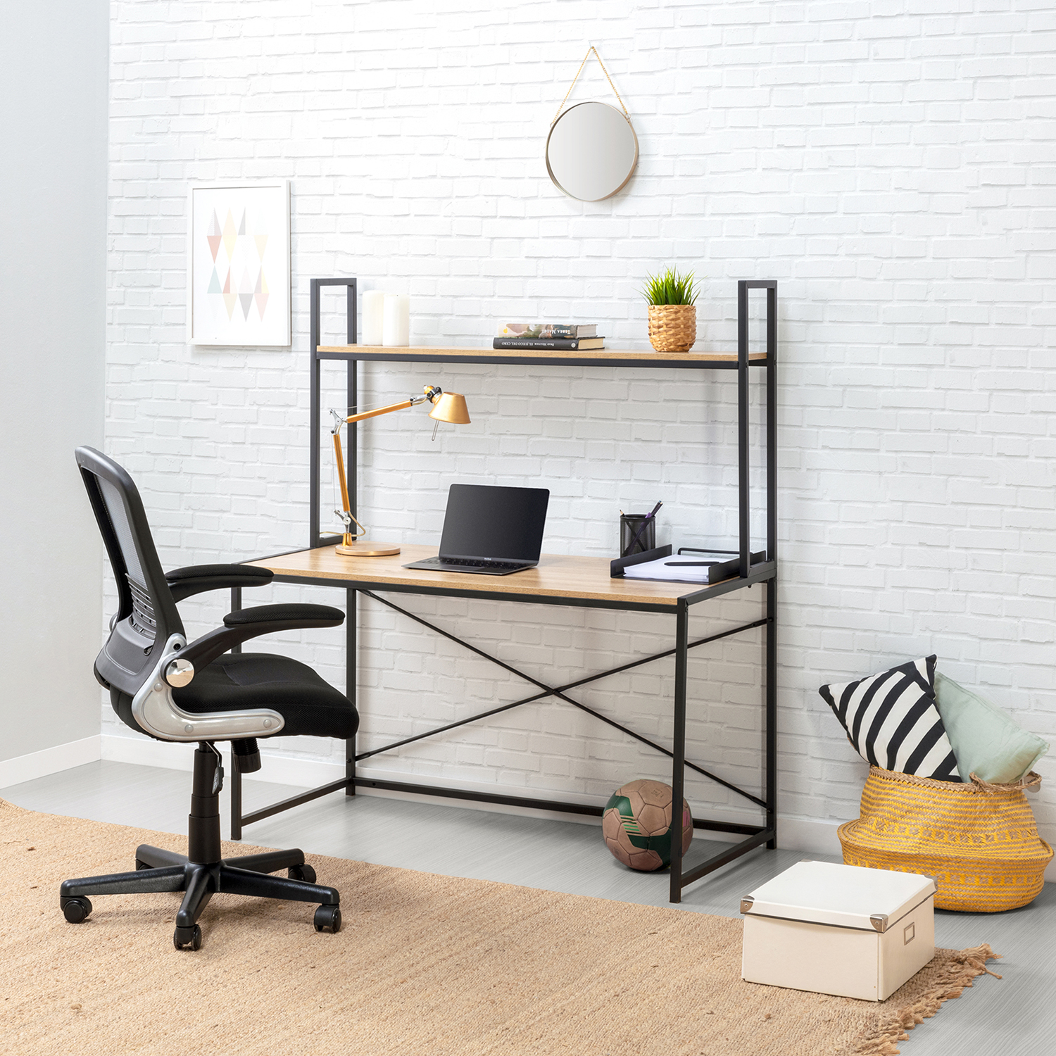 Una silla de oficina negra frente a un escritorio de madera con portátil, lámpara y estantes.