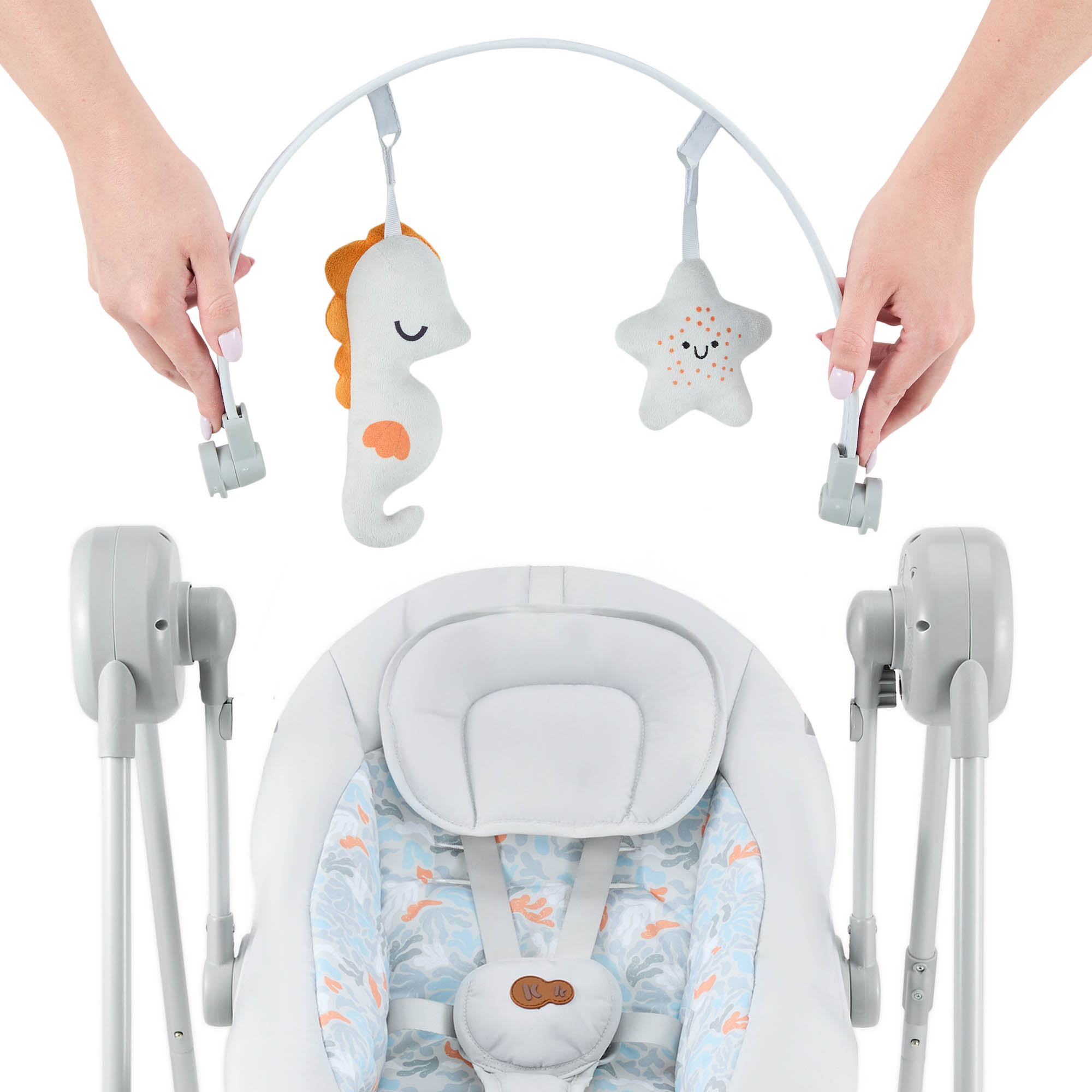 Hände befestigen Spielzeug an Babywippe mit Seepferdchen und Stern
