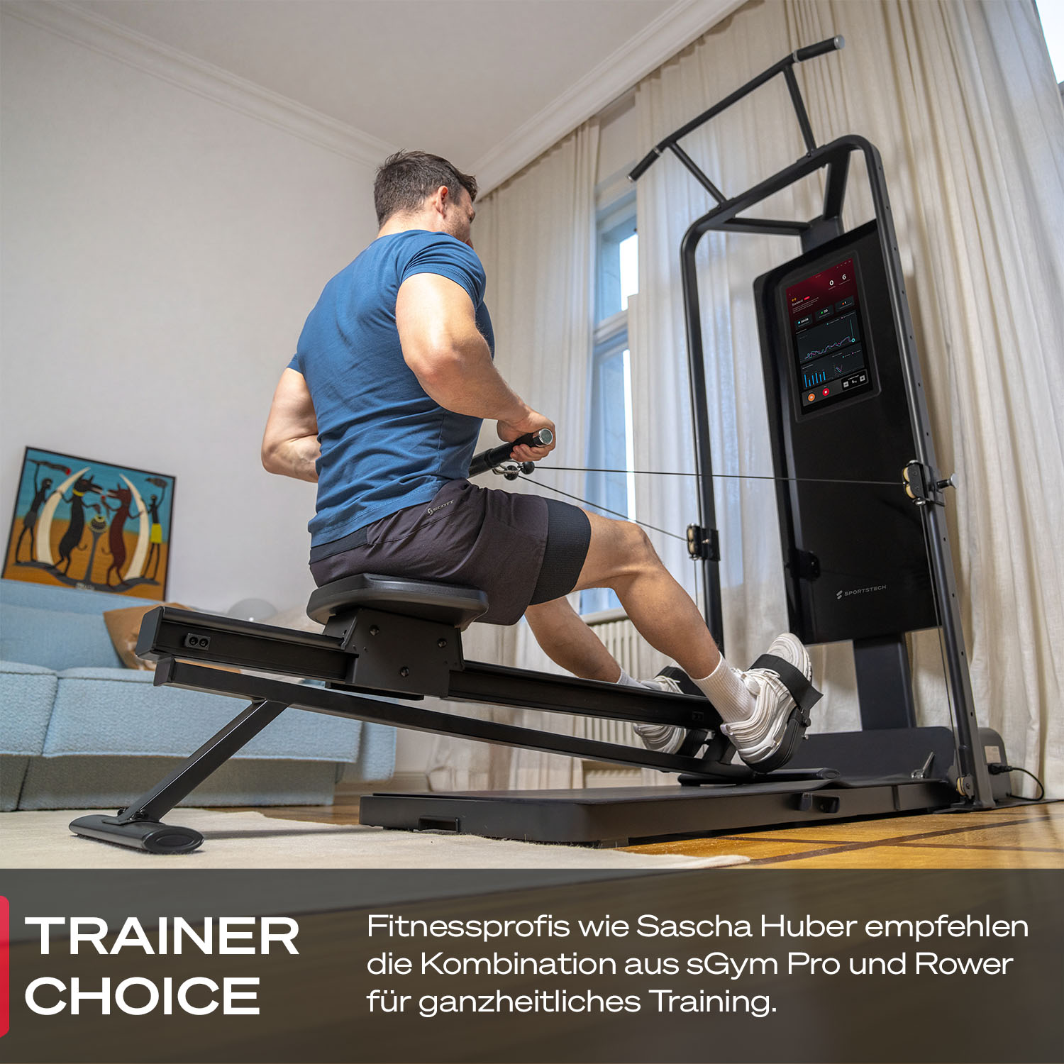 Ein Mann trainiert auf einem Rudergerät vor einem Bildschirm in einem Wohnzimmer.