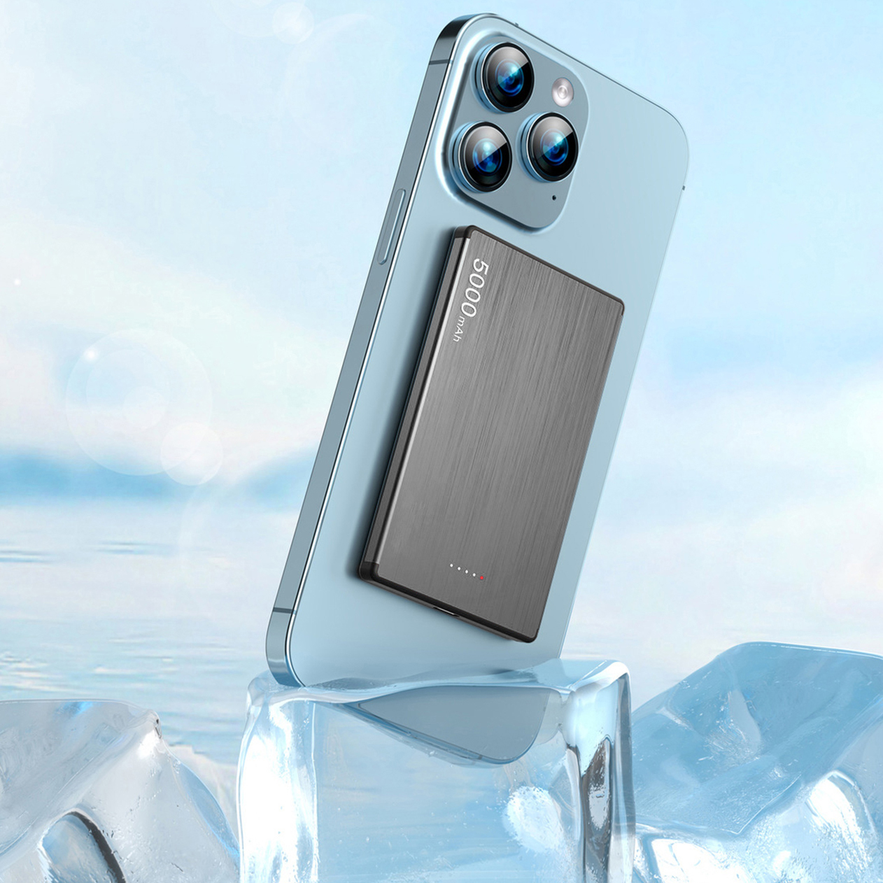 Uno smartphone blu con power bank poggia su cubetti di ghiaccio, cielo azzurro.