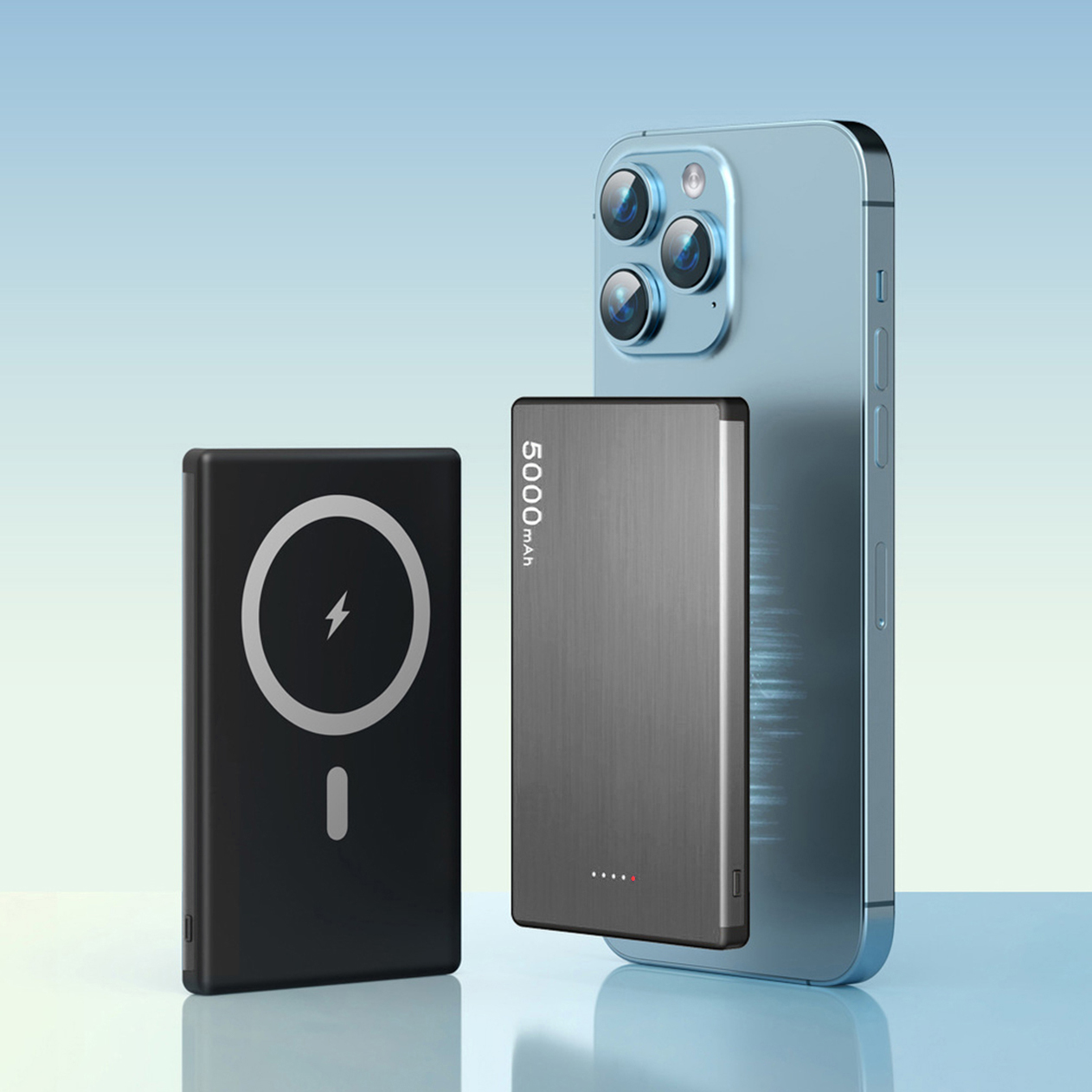Un iPhone blu accanto a un power bank nero e grigio. Entrambi su superficie blu.