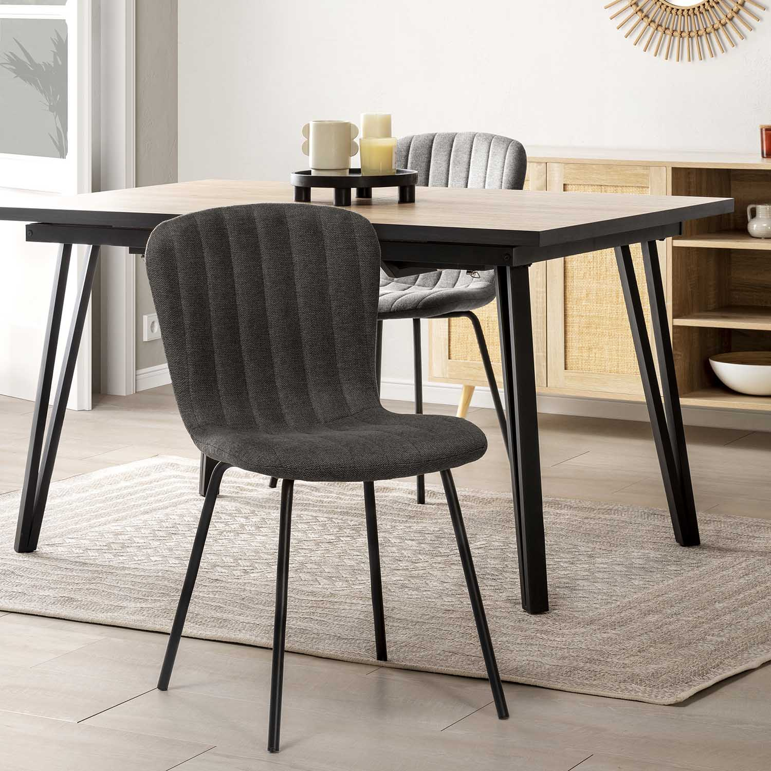 Silla gris oscuro acanalada delante de una mesa de madera con patas negras.