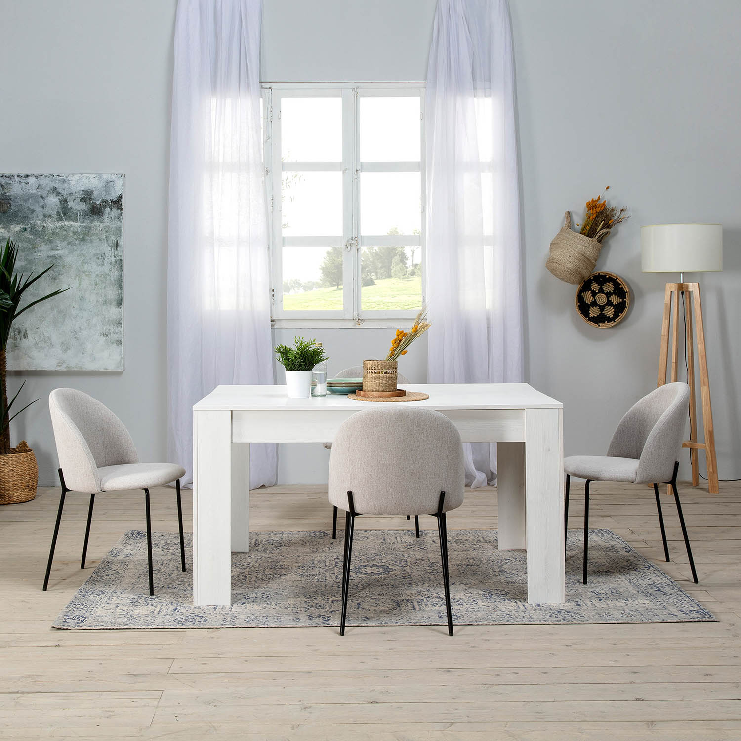 Una mesa de comedor blanca con cuatro sillas sobre una alfombra frente a una ventana.