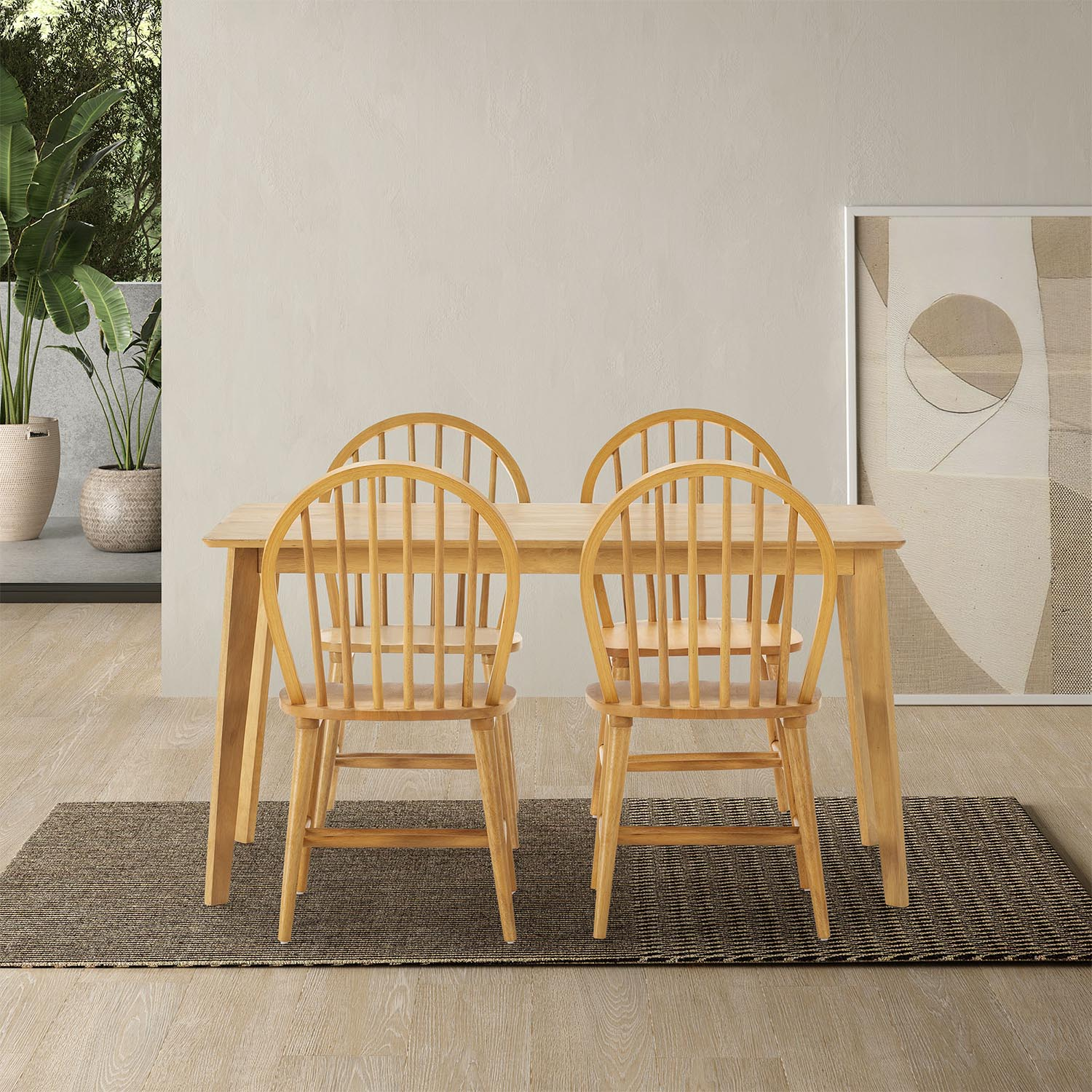 Una mesa de madera con cuatro sillas se asienta sobre una alfombra frente a una pared con arte.