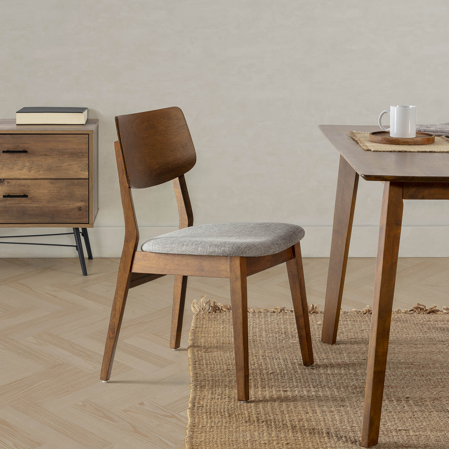 Una silla de comedor de madera con cojín gris junto a una mesa de madera.